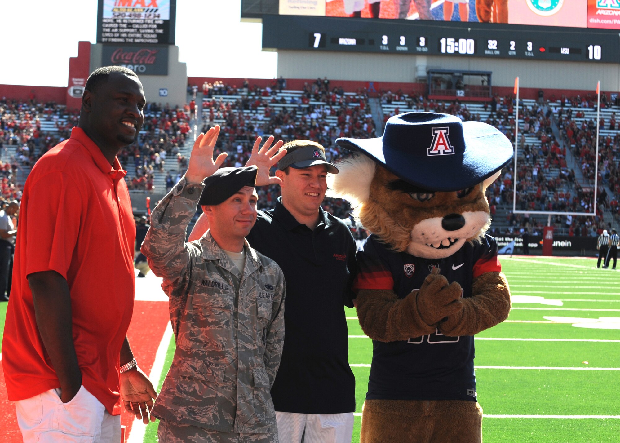 U.S. Air Force Senior Airman Gerard Waldbillig, 355th Security Forces Squadron, Davis-Monthan AFB, Ariz., stands on the field with ceremony sponsors and "Wilbur the Wildcat" while being honored during a "Welcome Home Heroes" ceremony right before the second quarter of a University of Arizona football game at Arizona Stadium, Tucson, Ariz., Nov. 16, 2013.  The ceremony recognizes military members who have recently returned home from deployments. (U.S. Air Force photo by Airman 1st Class Chris Massey/Released)