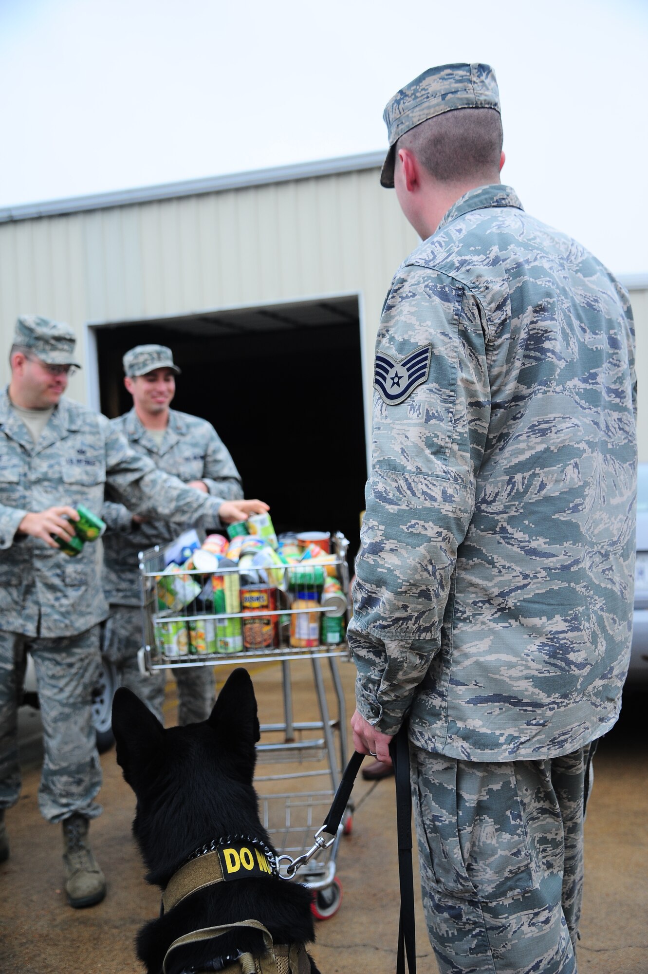 Tech. Sgt. Bryan Franks, 14th Flying Training Wing Public Affairs, and 2nd Lt. Cory Concha, 14th Student Squadron, collect cans from the Military Working Dog Demonstration to be donated to the United Way Nov. 22. One can of food was the entrance fee to the demonstration.  (U.S. Air Force Photo/Airman 1st Class Daniel Lile)