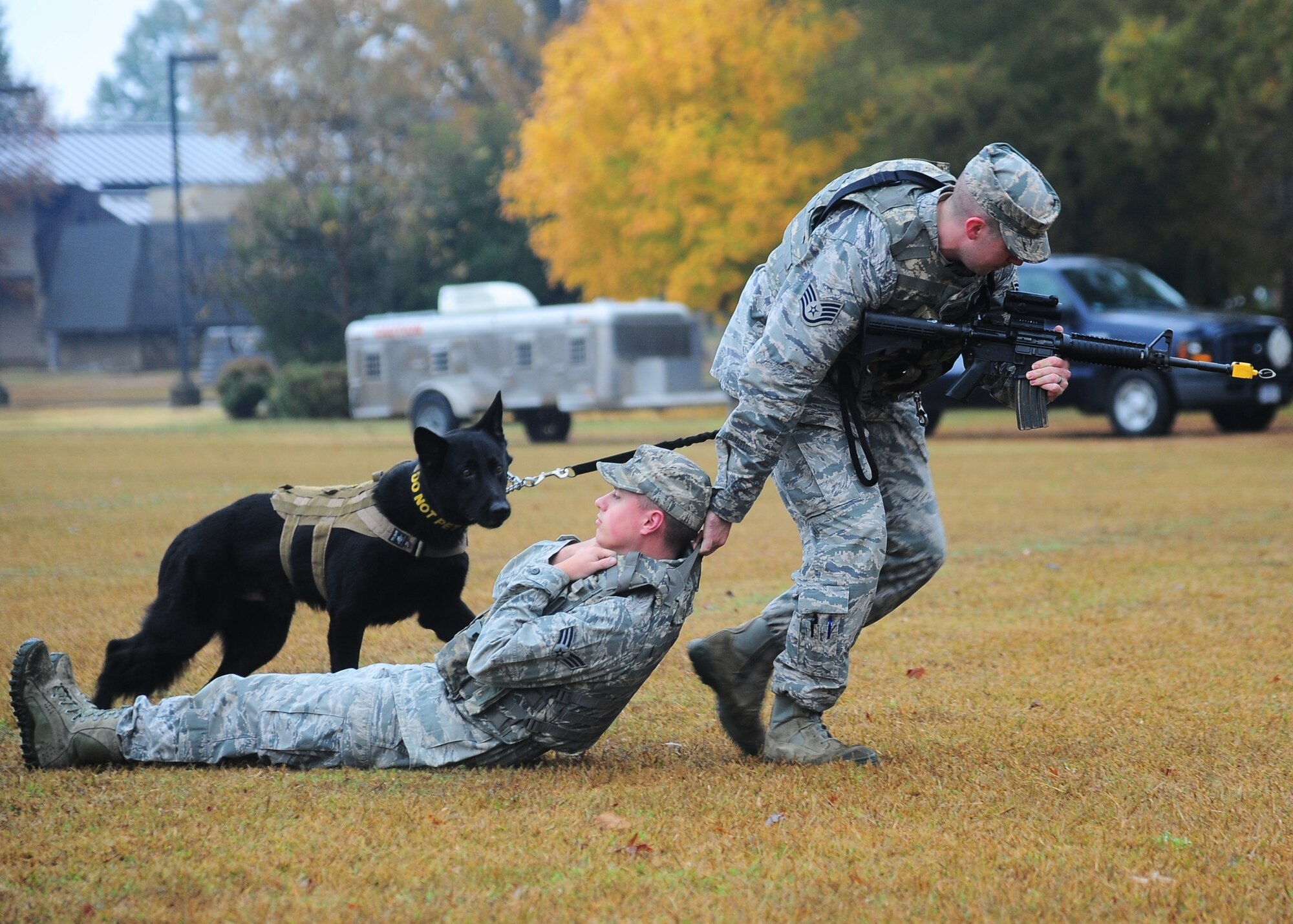 Staff Sgt.  Karl Stefanowicz, 14th Security Forces Squadron, drags an “injured” Airman while Maci, a military working dog, oversees the operation during the Military Working Dog Demonstration Nov. 22 outside of the Columbus Club. (U.S. Air Force Photo/Airman 1st Class Daniel Lile)