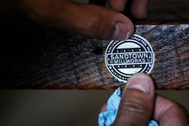 James Battaglia, general manager, adds the finishing touch at Sandtown Millworks in Baltimore, Md., Aug. 16, 2013.  Battaglia finished the table with a custom pewter emblem.  (U.S. Air Force photo by Tech. Sgt. Jasmin Taylor)