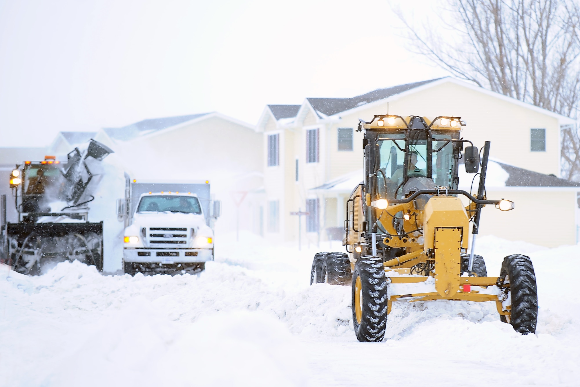 Members of the 5th Civil Engineering Squadron remove snow near houses at Minot Air Force Base. The 5th CES’ Snow Removal Section runs a 24/7 hour operation from the time of the first snowfall until the last one is anticipated. (U.S. Air Force photo/Airman 1st Class Kristoffer Kaubisch)