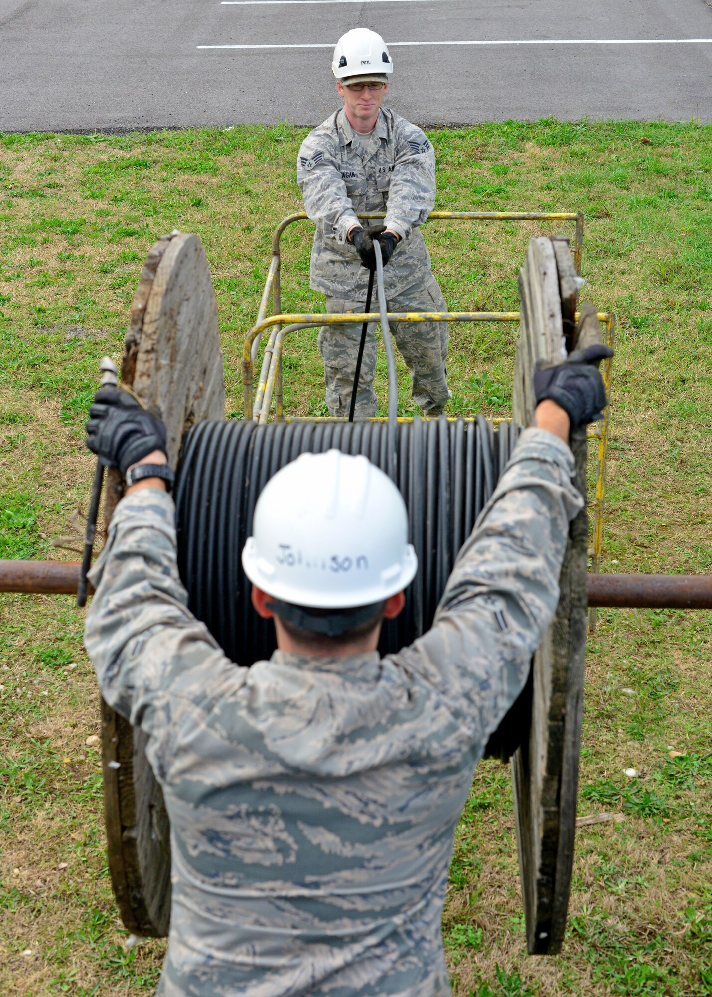 Senior Airman Kyle Ragan and Airman 1st Class Austin Johnson, 31st Communications Squadron cable systems apprentices, unwind a reel of cable into a manhole, Nov. 13, 2013, at Aviano Air Base, Italy. “Cable Dawgs” monitor and analyze performance of buried and aerial cable and antenna networks in support of everyday communications, surveillance systems, weapons storage security and even NATO operations. (U.S. Air Force photo/Airman 1st Class Abbey Whittaker) 