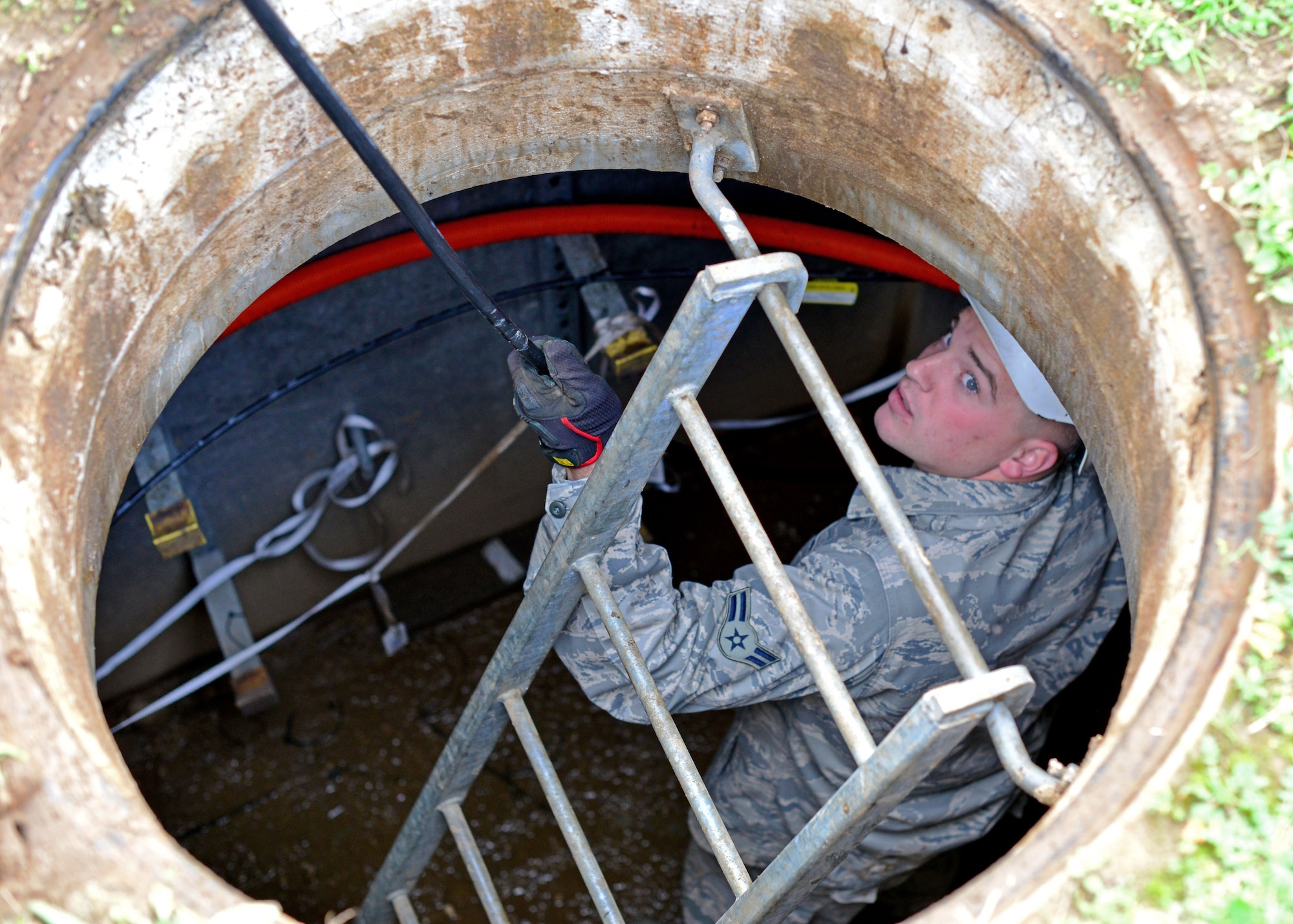 Airman 1st Class James Longmire, 31st Communications Squadron cable systems apprentice pulls a line of cable into a manhole, Nov. 13, 2013, at Aviano Air Base, Italy. Cable and antenna maintainers climb into man holes to install and maintain all communication lines above and below ground level. (U.S. Air Force photo/Senior Airman Briana Jones)