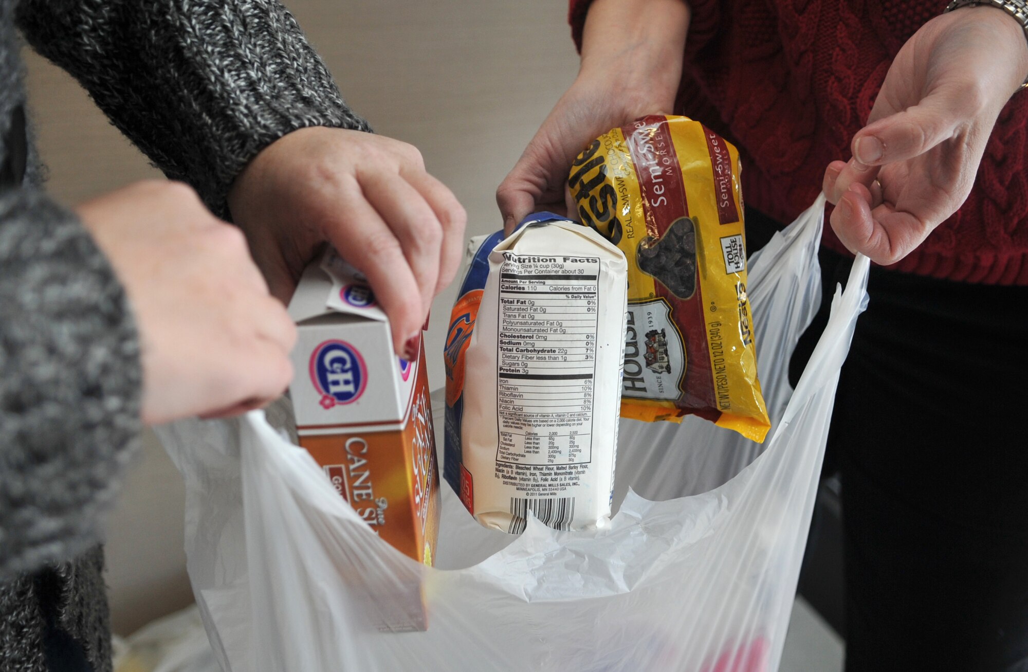 Christina Ellingson, left, spouse of U.S. Army Capt. Ed Ellingson, 35th Air Defense Artillery Brigade Public Affairs officer, and Landa Strunk, spouse of Col. Michael Strunk, 51st Mission Support Group commander, assemble a cookie-baking kit for Operation Sweet Treat at Osan Air Base, Republic of Korea, Nov. 26, 2013. Each kit consisted of enough flour, sugar, brown sugar, eggs, chocolate chips and butter to bake six dozen cookies. (U.S. Air Force photo/Airman 1st Class Ashley J. Thum)