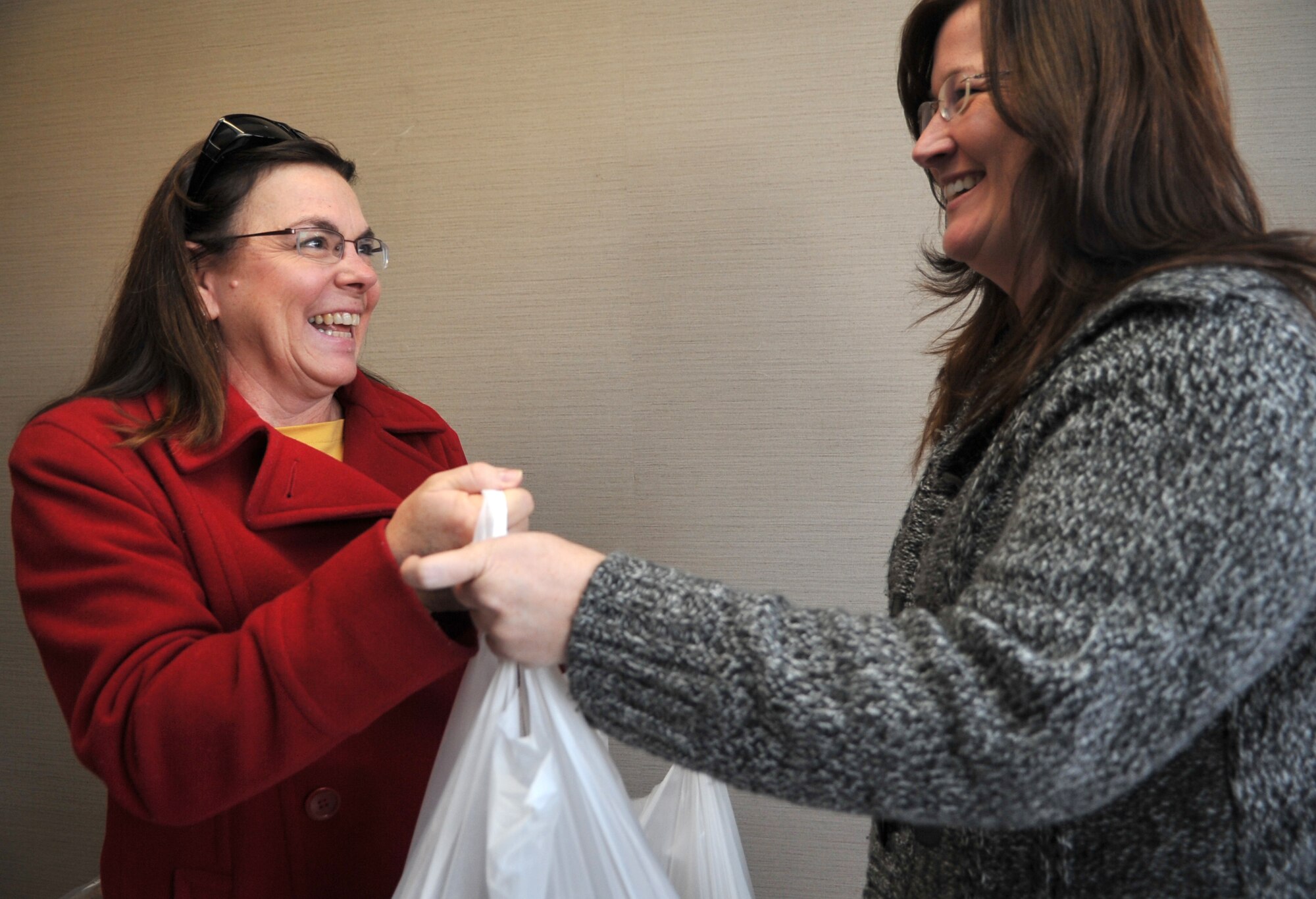 Susan McDonnell, left, spouse of Col. John McDonnell, 607th Air Operations Center chief of combat plans, picks up her cookie-baking kits for Operation Sweet Treat from Christina Ellingson, spouse of U.S. Army Capt. Ed Ellingson, 35th Air Defense Artillery Brigade Public Affairs officer, at Osan Air Base, Republic of Korea, Nov. 26, 2013. Nearly 50 people flooded the commissary to take home one or more of the 114 kits the Operation Sweet Treat crew, with the help of donations from the commissary, had assembled. (U.S. Air Force photo/Airman 1st Class Ashley J. Thum)