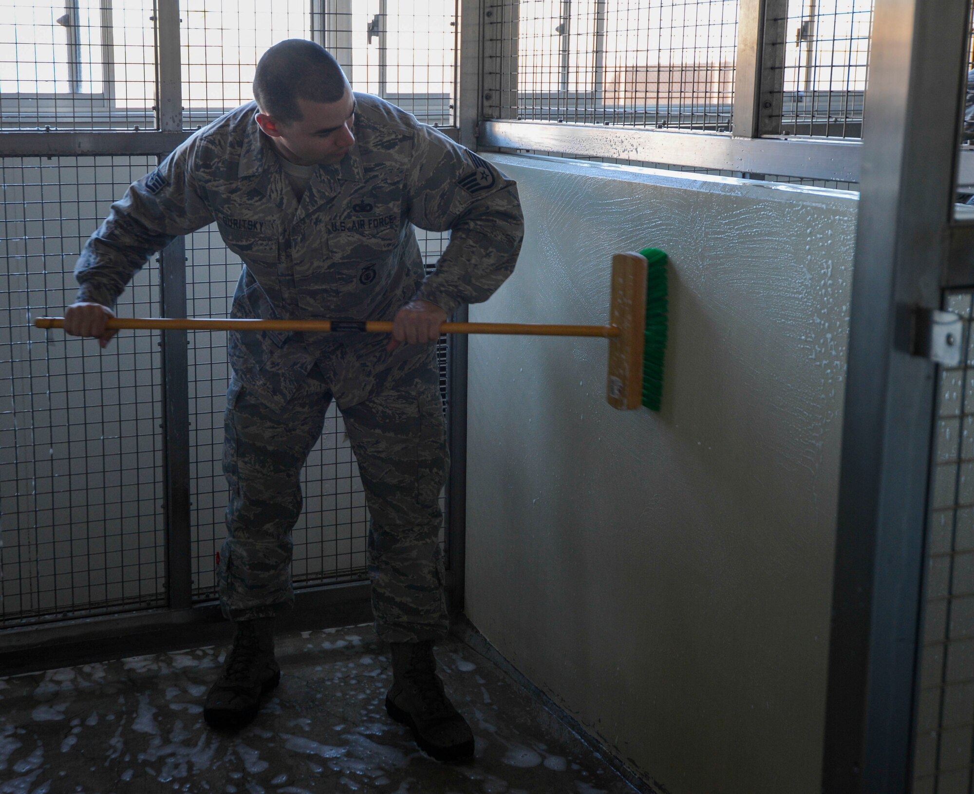 Staff Sgt. David Duritsky, 374th Security Forces Squadron military working dog kennel master, scrubs the kennels at Yokota Air Base, Japan, Nov. 22, 2013.  Kennels are cleaned frequently to ensure they are clean and healthy as possible for the canines. (U.S. Air Force photo by Airman 1st Class Meagan Schutter/Released)