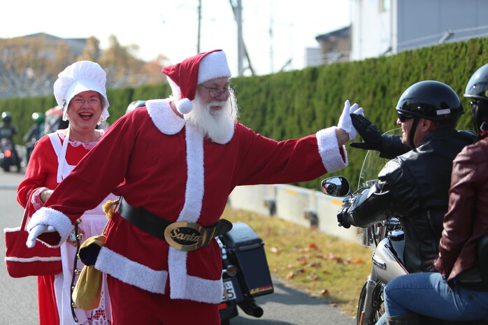 Mr. and Mrs. Claus, portrayed by John and Jan Jenson, walk down the road and high-five a motorcycle rider during the Motorcycle Rally and Toy Drive event hosted by the Marine Thrift Store aboard Marine Corps Air Station Iwakuni, Japan, Nov. 24, 2013. Mr. and Mrs. Claus helped collect the donated toys from the event, as well as walked down the road to greet the riders and gave a little ‘ho ho ho’ Christmas spirit encouragement.