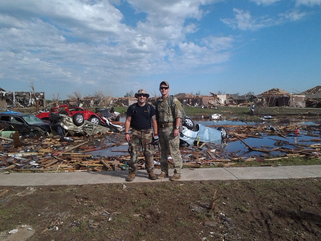 Eric Calley, left, poses with a friend at a tornado-ravaged site in Oklahoma where the two volunteered assistance earlier this year.