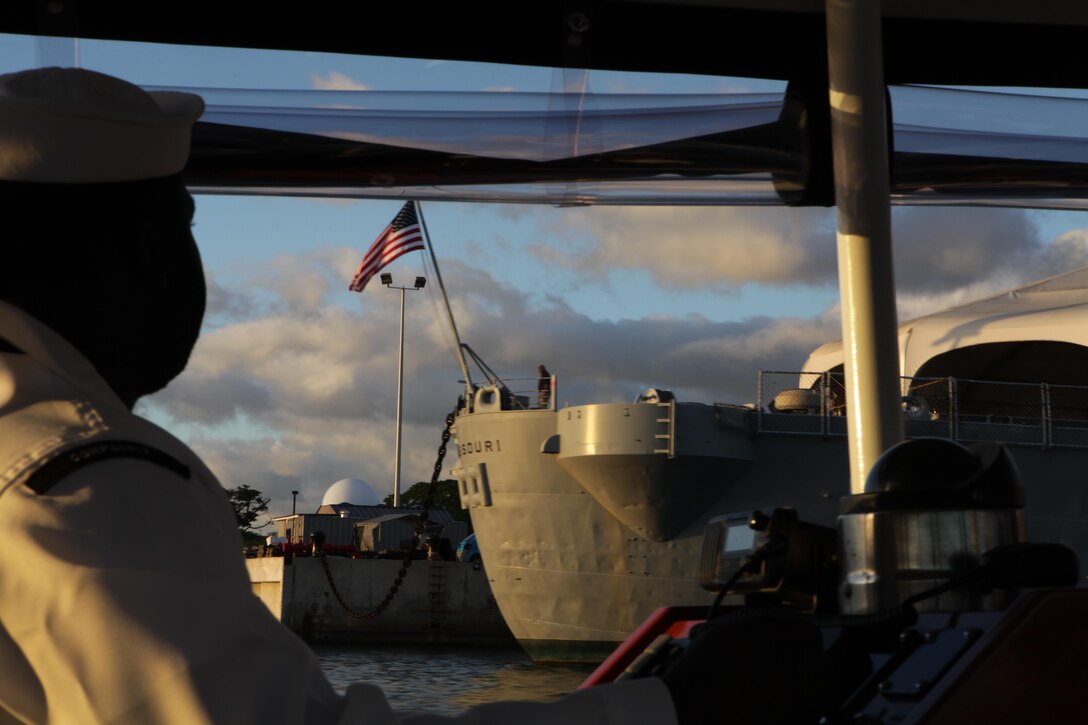 Petty Officer 2nd Class Jon-Pierre Stewart, drives the Remembrance barge past the USS Missouri here Nov. 25. Stewart was in charge of transporting members of the Chaplain Corps to the USS Arizona Memorial during a barge tour in remembrance of the fallen victims of the attack on Pearl Harbor.