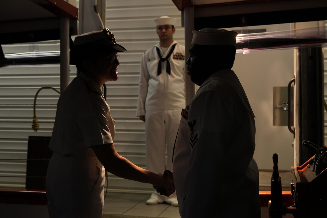 Petty Officer 1st class Scott Burroughs, a boatswains mate with U.S. Pacific Fleet, awaits Rear Adm. Margaret Grun Kibben, Chaplain of the Marine Corps (left), as she shakes hands with Petty Officer 2nd class Jon-Pierre Stewart, an engineer with PACFLT, before she disembarks the Remembrance barge at the end of the tour here Nov. 25. Members of the Chaplain Corps visited the USS Arizona Memorial in order to pay tribute to the fallen heroes who lost their lives during the attack on Pearl Harbor, Dec. 7, 1941.
