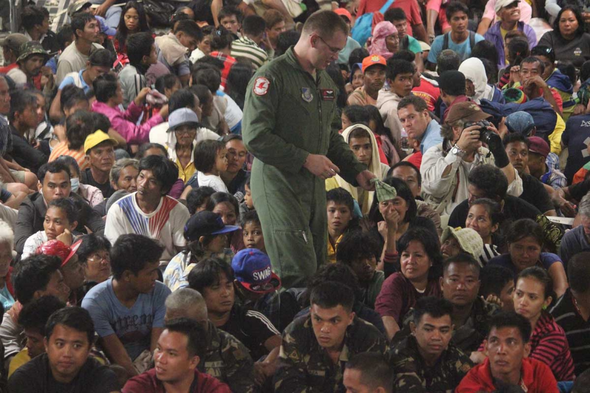 U.S. Air Force Staff Sgt. Neal Ylitalo, 517th Airlift Squadron C-17 Globemaster III loadmaster, walks through a large group of evacuees during Operation Damayan, Nov. 21. Operation Damayan is a humanitarian aid and disaster relief operation led by the Philippine government and supported by a multinational response force. The evacuee transportation process was overseen by a joint service operation and the Armed Forces of the Philippines. (Courtesy photo)