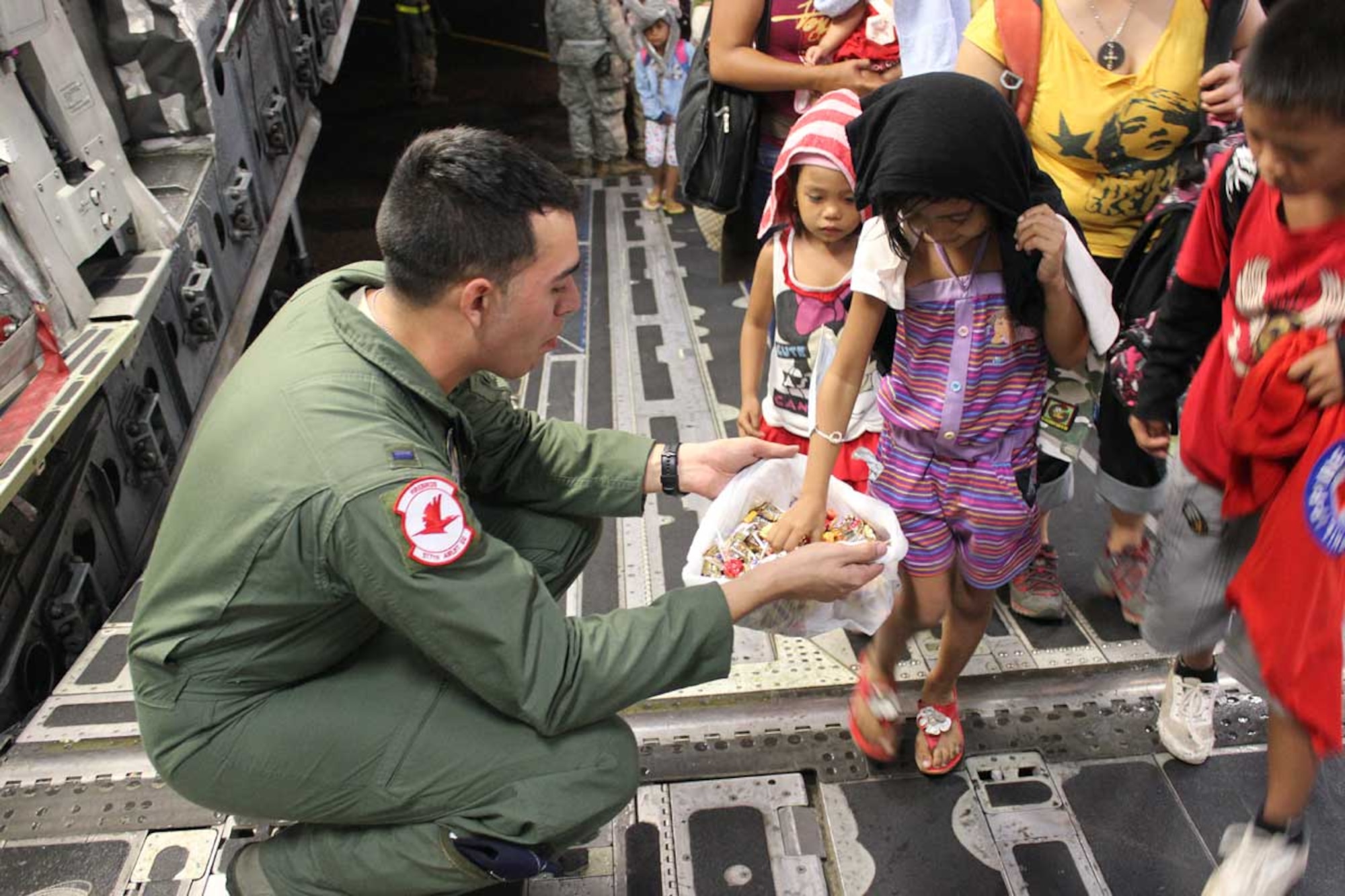 U.S. Air Force 1st Lt. Evan Lomeli, 517th Airlift Squadron C-17 Globemaster III pilot, hands out candy to children as they board a C-17 to be transported within the Philippines as part of Operation Damayan, Nov. 21. Operation Damayan is a humanitarian aid and disaster relief operation led by the Philippine government and supported by a multinational response force. The transport process was overseen by a joint service operation and the Armed Forces of the Philippines. (Courtesy photo)