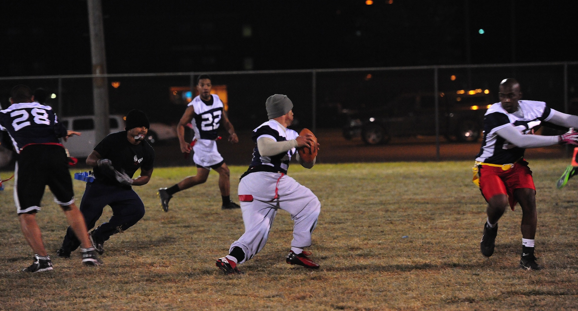 James Hudson, 509th Force Support Squadron quarterback, evades defenders to throw to an open receiver during an intramural flag football championship game against the 509th Aircraft Maintenance Squadron at Whiteman Air Force Base, Mo., Nov. 15, 2013. FSS only had seven players who stayed on the field the entire duration of the game to contend against AMXS, who had more than 20 players to work with. In spite of the fact that FSS didn’t have any players to sub in or out, they were still able to hold AMXS to a close game until the fourth quarter. (U.S. Air Force photo by Staff Sgt. Nick Wilson/Released)