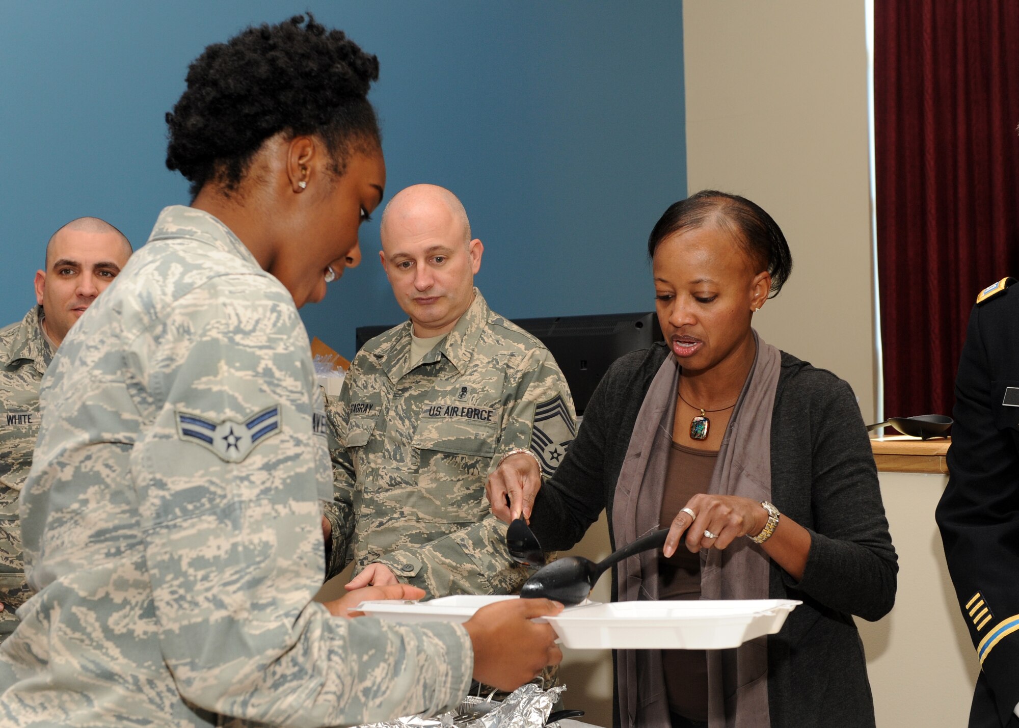 Travelle Wright, wife of Col. Dan Wright, 460th Space Wing commander, serves food to Airman 1st Class Chanel Davenport, 460th Space Communication Squadron, Nov. 27, 2013, at the Panther Hall Dorm on Buckley Air Force Base, Colo. This is an annual tradition to ensure wellness, show thanks to and provide a home-cooked meal for Airmen, Soldiers, Sailors, Marines and Coast Guardsmen in the dorm. (U.S. Air Force photo by Senior Airman Marcy Copeland/Released)  