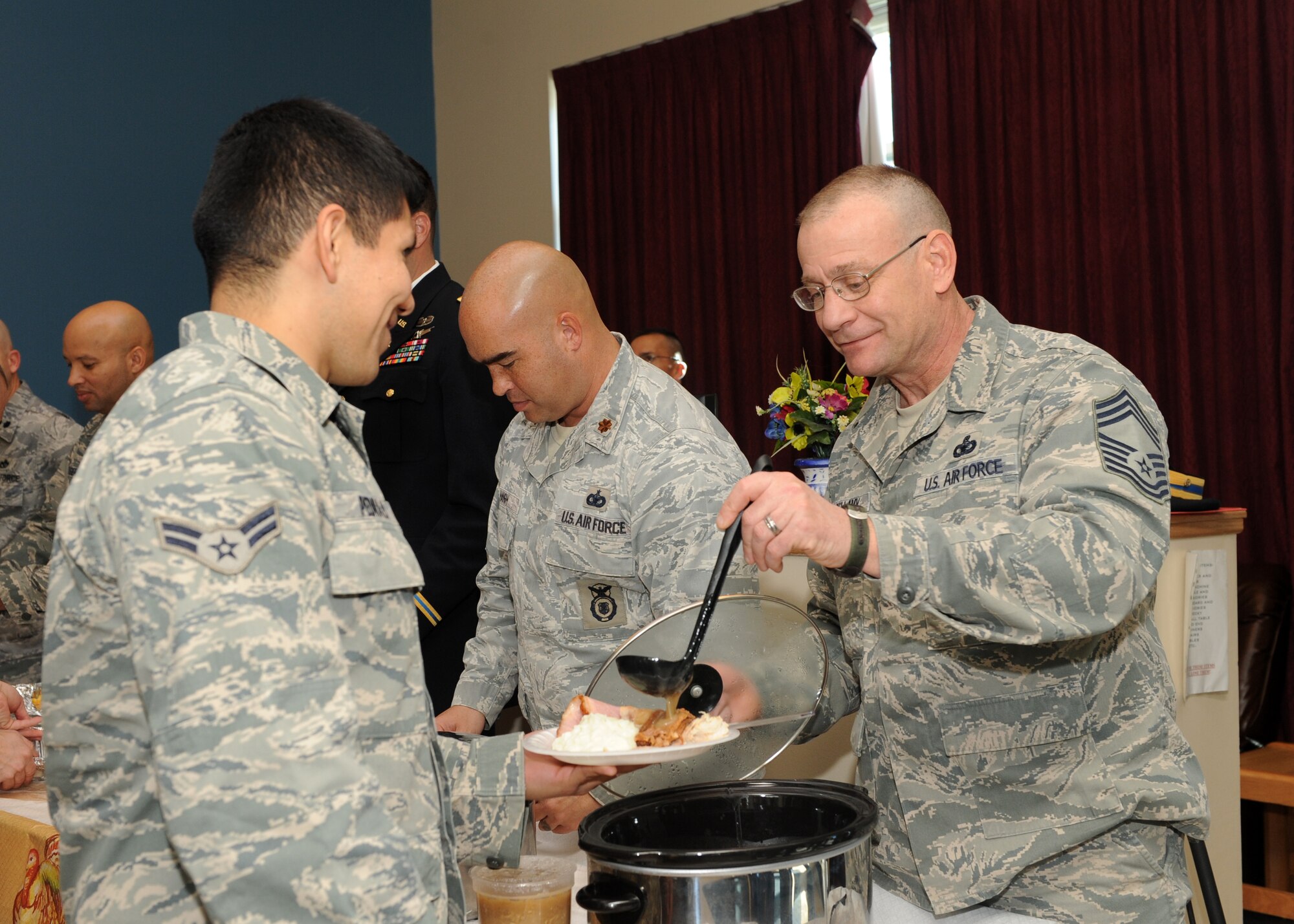 Chief Master Sgt. Howard Bellamy II, 460th Security Forces Squadron security forces manager, ladles gravy for Airman 1st Class Kevin Pedraza, 460th Contracting Flight, Nov. 27, 2013, at the Panther Hall Dorm on Buckley Air Force Base, Colo. This is an annual tradition to ensure wellness, show thanks to and provide a home-cooked meal for Airmen, Soldiers, Sailors, Marines and Coast Guardsmen in the dorm. (U.S. Air Force photo by Senior Airman Marcy Copeland/Released)  