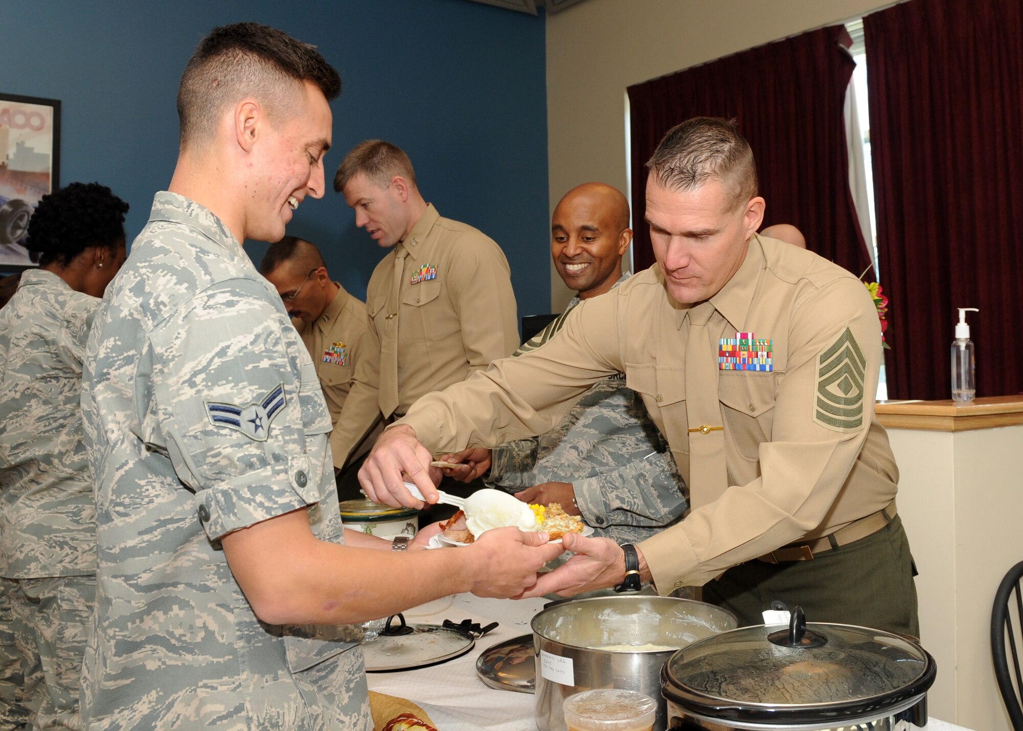 1st Sgt. Jon Jerome, Quebec Battery, 5th Battalion, 14th Marine Regiment, 4th Marine Division inspector-instructor first sergeant, serves mashed potatoes to Airman 1st Class John T. Moody III, 460th Space Communications Squadron, Nov. 27, 2013, at the Panther Hall Dorm on Buckley Air Force Base, Colo. This is an annual tradition to ensure wellness, show thanks to and provide a home-cooked meal for Airmen, Soldiers, Sailors, Marines and Coast Guardsmen in the dorm. (U.S. Air Force photo by Senior Airman Marcy Copeland/Released)  