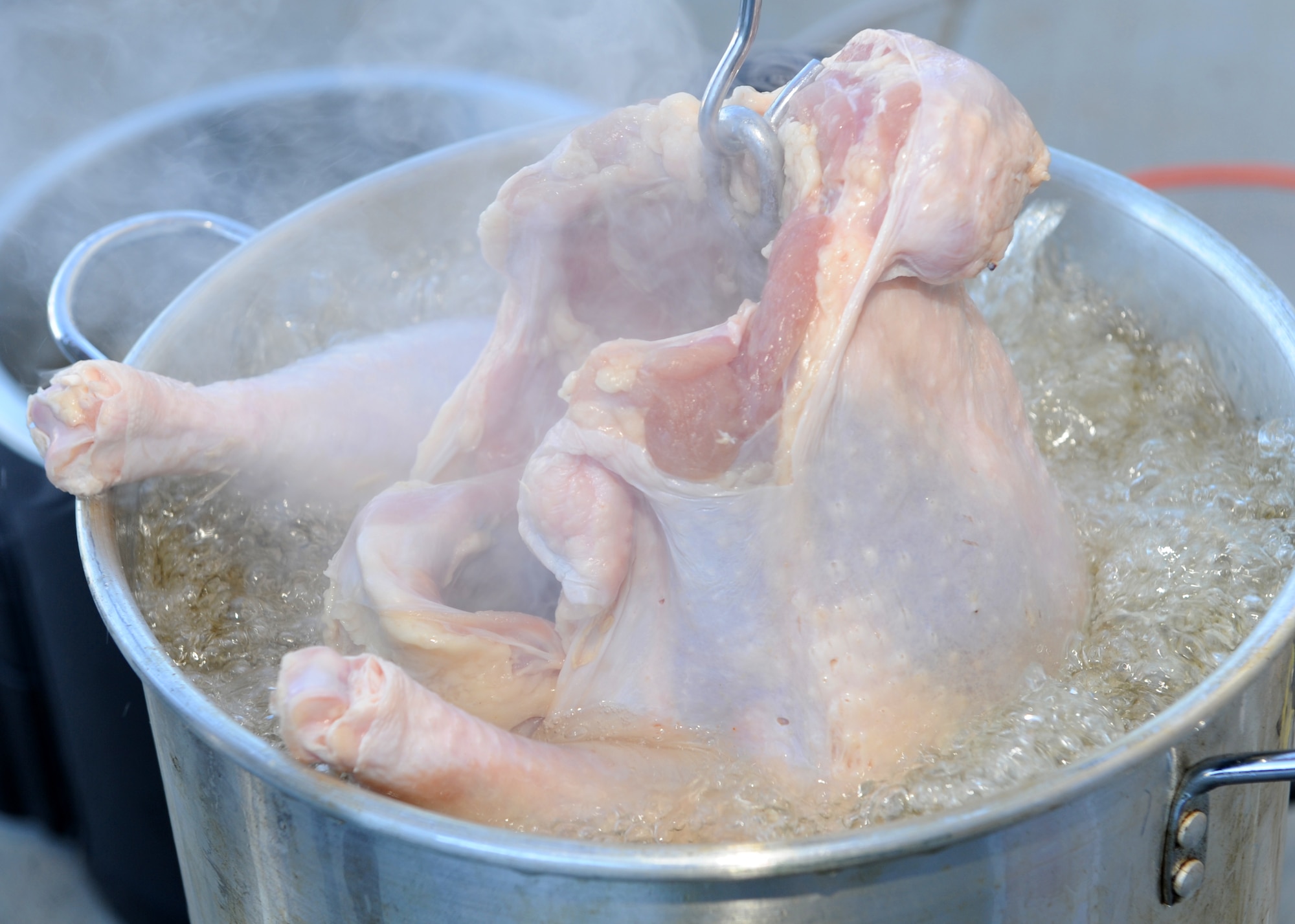 A turkey is put into hot peanut oil Nov. 27, 2013, at the Panther Hall Dorm on Buckley Air Force Base, Colo. This is an annual tradition to ensure wellness, show thanks to and provide a home-cooked meal for Airmen, Soldiers, Sailors, Marines and Coast Guardsmen in the dorm. (U.S. Air Force photo by Senior Airman Marcy Copeland/Released)  