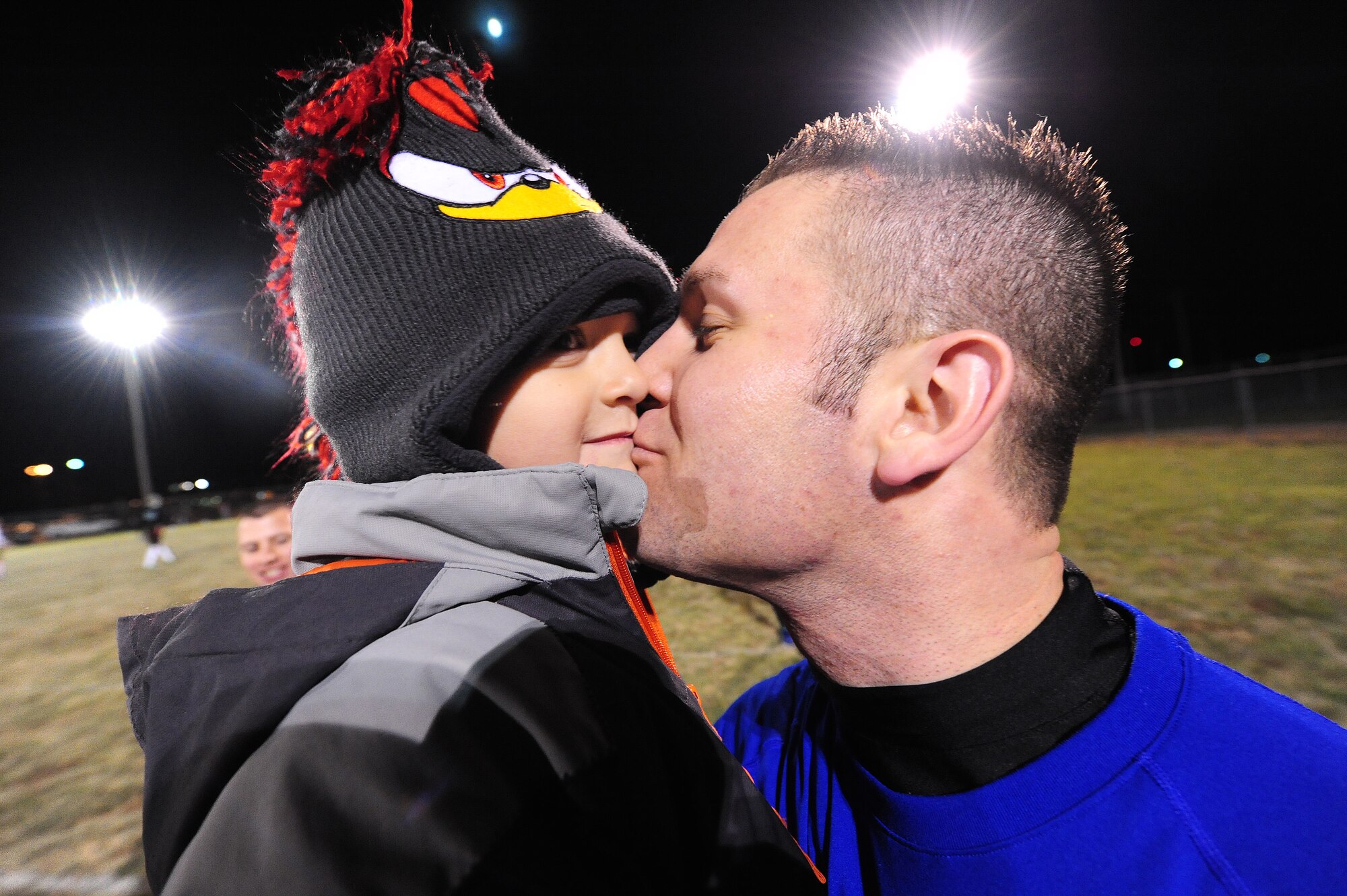 Trajen Chastain, 509th Logistics Readiness Squadron intramural flag football team member, kisses his 4-year-old son Kaiden after winning a semifinal playoff game at Whiteman Air Force Base, Mo., Nov. 14, 2013. The LRS team defeated the 709th Munitions Support Squadron 34-14 to advance to the final round of the playoffs. (U.S. Air Force photo by Staff Sgt. Nick Wilson/Released)