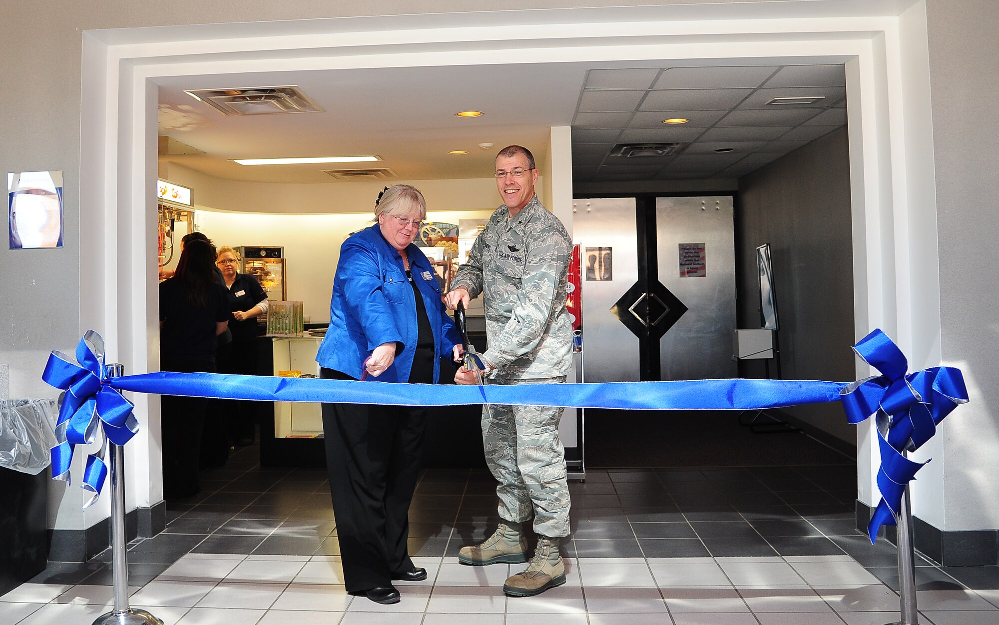 U.S. Air Force Brig. Gen. Thomas A. Bussiere, right, 509th Bomb Wing commander, and Paula Manning, Army and Air Force Exchange Service general manager, cut the ribbon at the Whiteman Theater grand re-opening Nov. 27, 2013, at Whiteman Air Force Base. After under-going $200,000 worth of renovations, the theater now features a brand-new projector and digital screen capable of showing 3-D movies. (U.S. Air Force photo by Staff Sgt. Brigitte N. Brantley/Released)