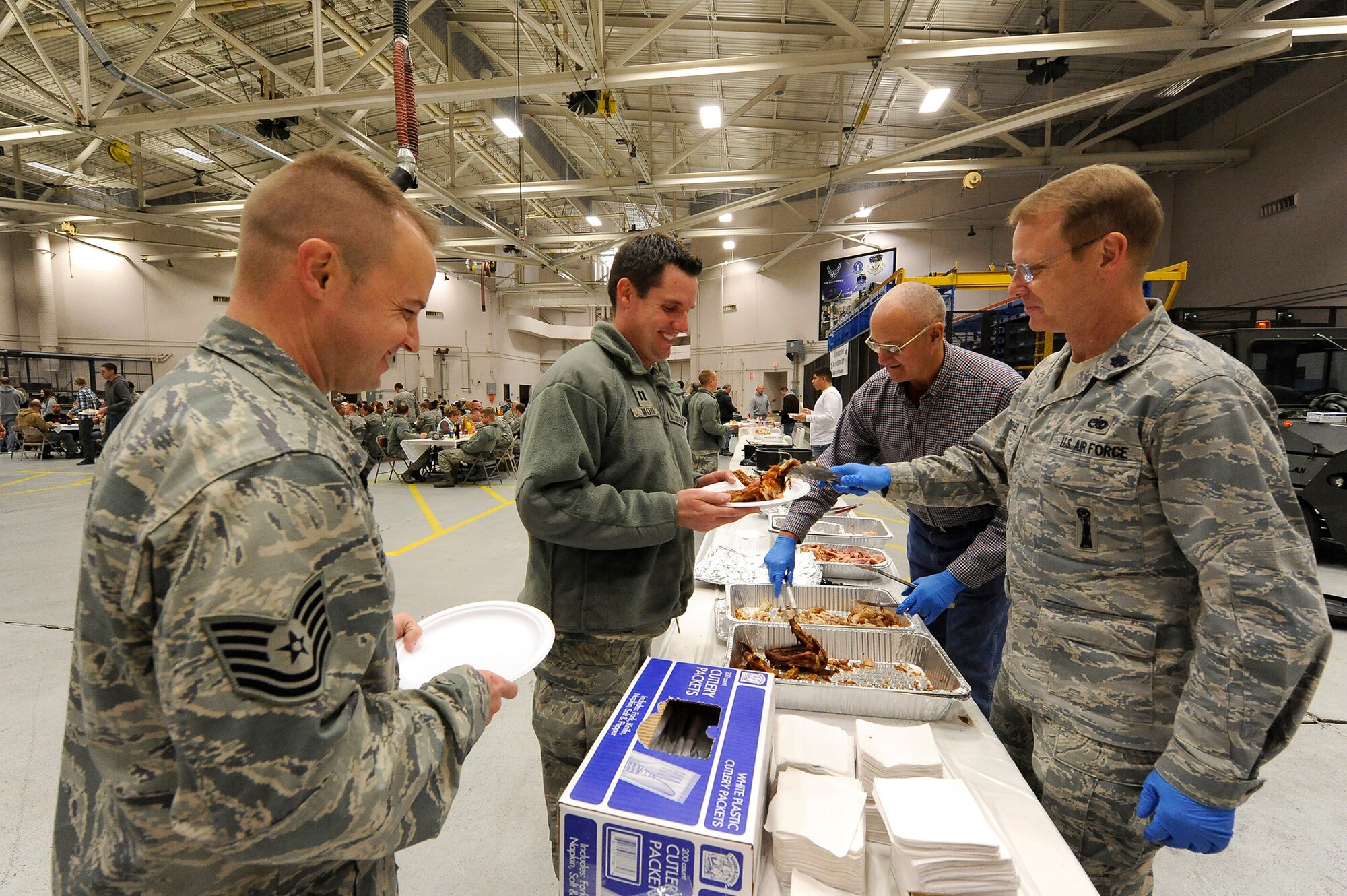 Tech. Sgt. Shane Rushforth, 341st Missile Wing chapel resource management  NCO in charge (left), and Chaplain (Capt.) Robert Mohr, 341st Missile Wing chaplain, receive generous amounts of turkey from Lt. Col. Keith Hepler, 341st Maintenance Group deputy group commander (right), during the 341st Maintenance Group’s annual Turkey Feed Nov. 22. More than 10 turkeys were served to hungry guests during the event. (U.S. Air Force photo/Airman 1st Class Collin Schmidt)