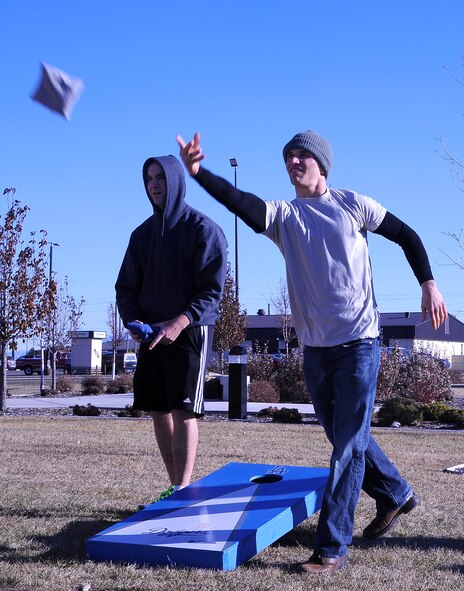 Airman 1st Class Darren Pack, 341st Contracting Squadron contracting specialist (right), tosses a bean bag during a game of cornhole as his rival, Airman 1st Class Colton Abernathy, 341st CONS contracting apprentice, watches. During the event, several groups went head-to-head to compete for the coveted WSS trophy. (U.S. Air Force photo/Airman 1st Class Collin Schmidt)