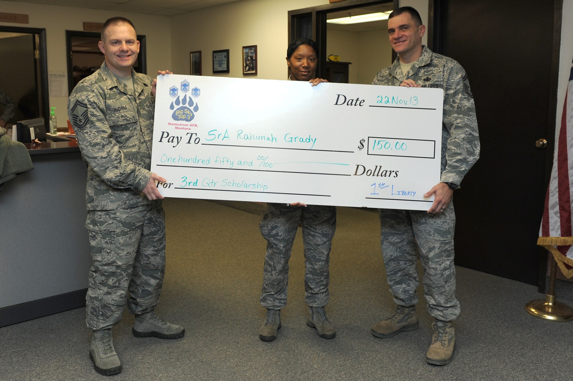Senior Airman Rahimah Grady, 341st Missile Security Forces Squadron member (center), receives a check from Senior Master Sgts. William Kudrna, 341st Comptroller Squadron superintendent (left), and Paul Stansbury, 341st Security Forces Group Tactical Response Force Operations superintendent, at the 341st MSFS command section Nov. 22. Grady was the Airman recipient of the Big Sky Top 3 Association third quarter scholarship for her essay regarding the fairness of the Air Force physical training program. The Top 3 Association offers quarterly scholarships to personnel ranked airman basic through technical sergeant. (U.S. Air Force photo/Senior Airman Katrina Heikkinen)