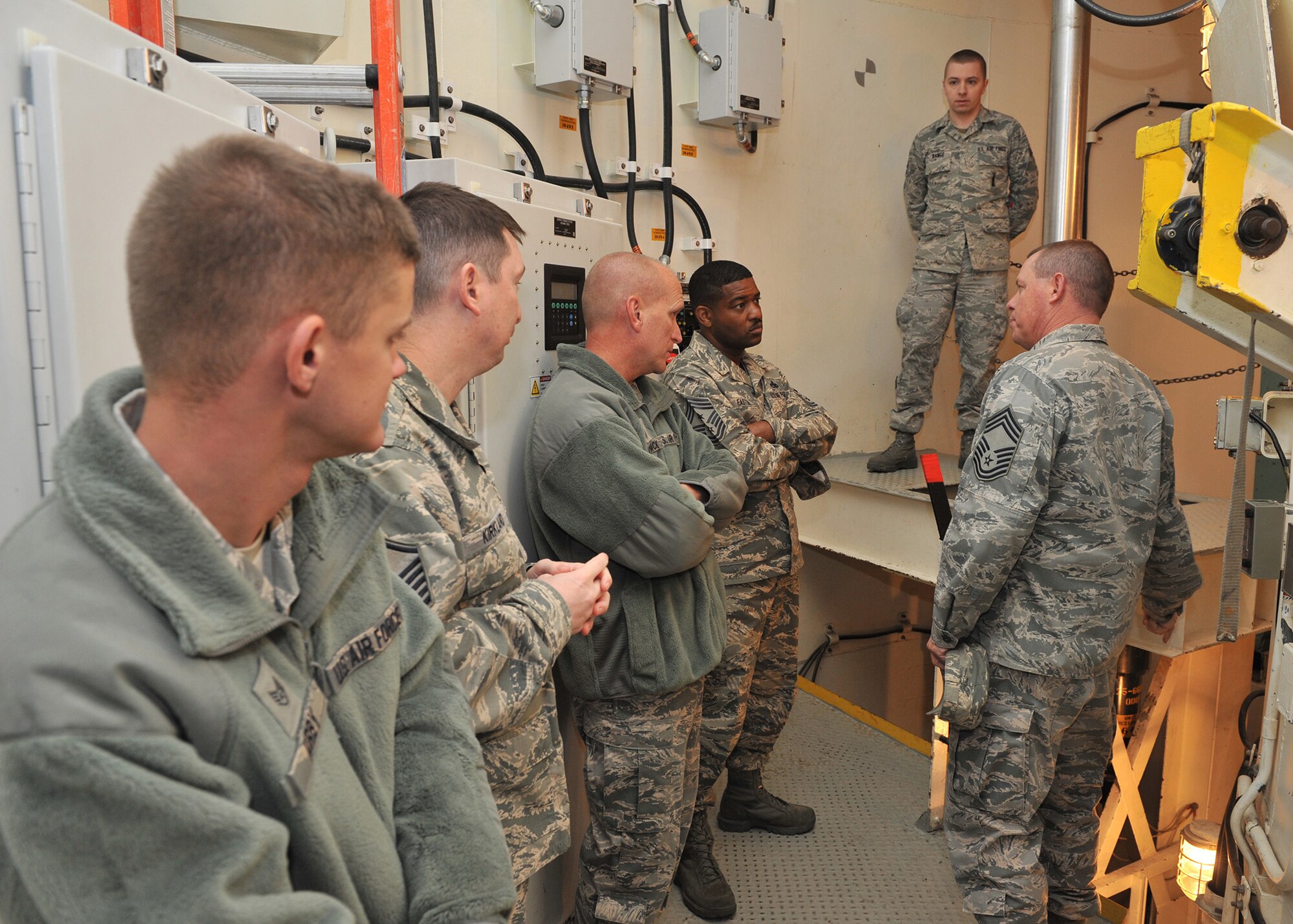 Chief Master Sgts. Brian Hornback, Air Force Global Strike Command chief (center left), and Phillip Easton, 341st Missile Wing command chief (center right), listen to Chief Master Sgt. Philip Lemaitre, 341st Maintenance Operations Squadron maintenance advisor (right), and other maintenance Airmen discuss the duties and the importance of training during their tour of the T-9 maintenance trainer Nov. 21. Hornback also toured the K-9 facility, military personnel section and Airman Leadership School during his visit to the base Nov. 20 and 21. (U.S. Air Force photo/John Turner)