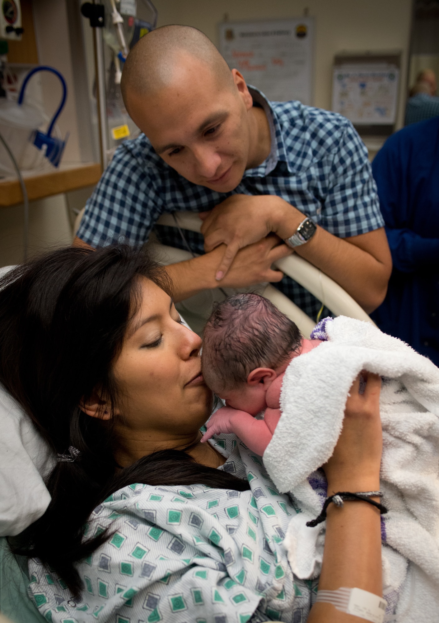Capt. Savannah Mendez places the first of many kisses on the forehead of her newborn girl as her husband Jon looks on. (U.S. Air Force photo/Ken Wright)