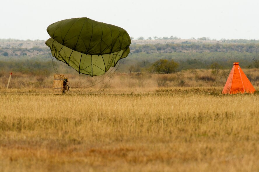 A cargo bundle lands Nov. 21, 2013, during Impact Day at a drop zone near Bronte, Texas. Impact Day gave maintainers from the 317th Airlift Group the opportunity to fly aboard a C-130J Super Hercules as it dropped cargo bundles at a designated drop zone. The Orange marker marks the designated drop target area. (U.S. Air Force photo by Airman 1st Class Justin Wright/Released)