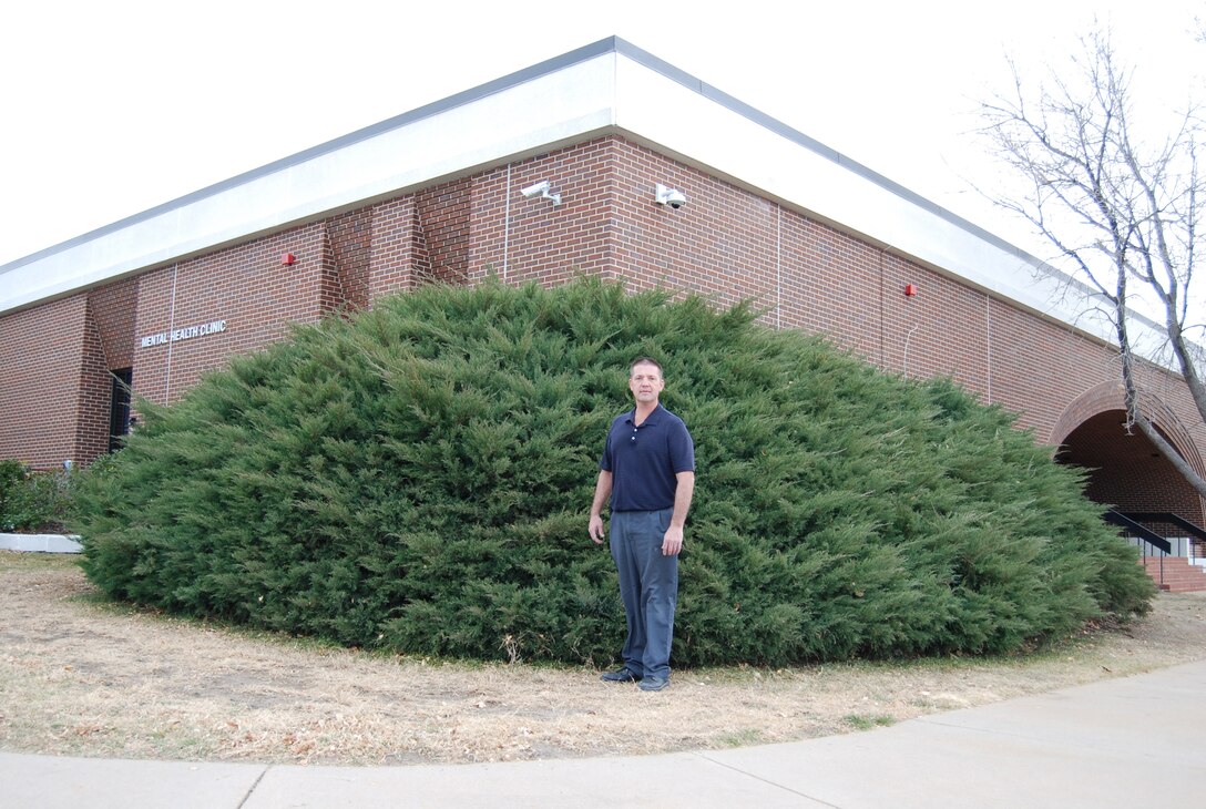 PETERSON AIR FORCE BASE, Colo. – Steven Tavernaro, 21st Medical Group building maintenance and contract manager, stands in front of the juniper bush that protected Debra Castle’s wallet from the weather for three decades. The wallet was discovered when branches were cut away to inspect the corner of the building. It has since been returned to Castle, now 60 and living in Oklahoma. (U.S. Air Force photo/Michael Golembesky)