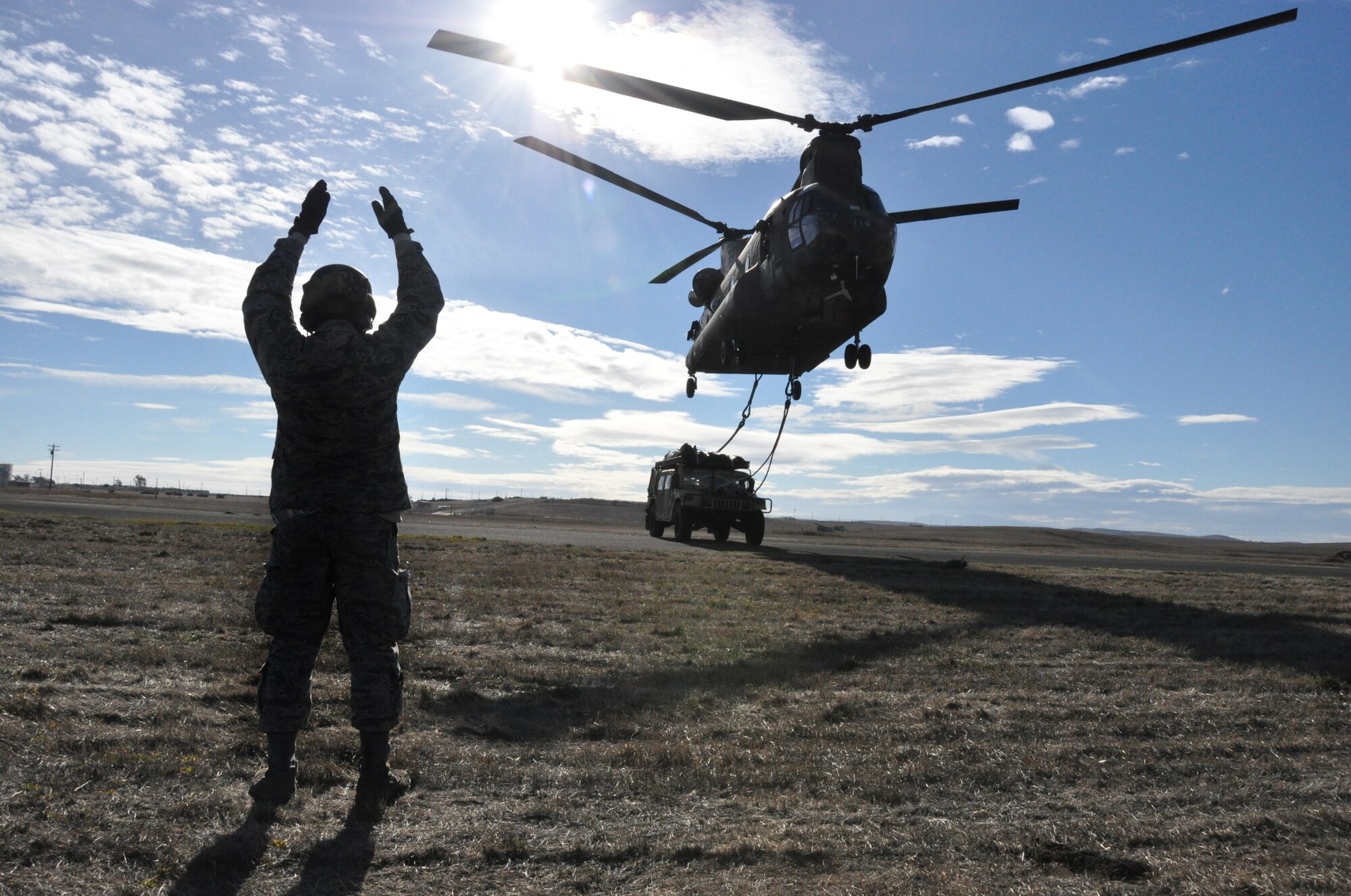 Staff Sgt. Ryan Torralba, 60th Aerial Port Squadron aerial porter, marshals a CH-47 Chinook as it picks up a humvee with a cargo sling Nov. 21 on Travis. (U.S. Air Force photo/Staff Sgt. Patrick Harrower)