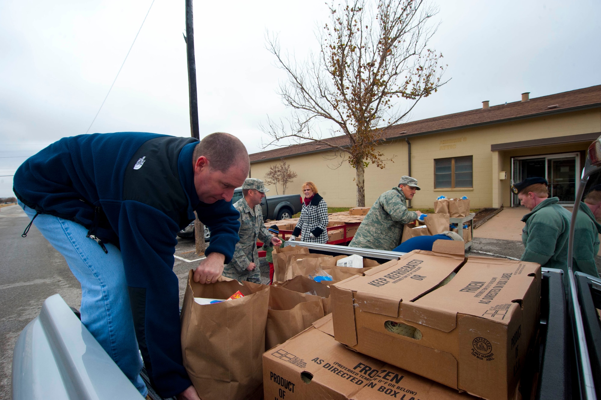 A food drive took place at the Airmen and Family Readiness Center here, so families could have the opportunity to enjoy a tasty holiday cheer Nov. 22-26. Around 7300 pounds of food and 249 turkeys were being prepared, as a gaggle of volunteers went around in a circle putting food supplies in bags. (U.S. Air force photo by Airman 1st Class Jelani Gibson) 