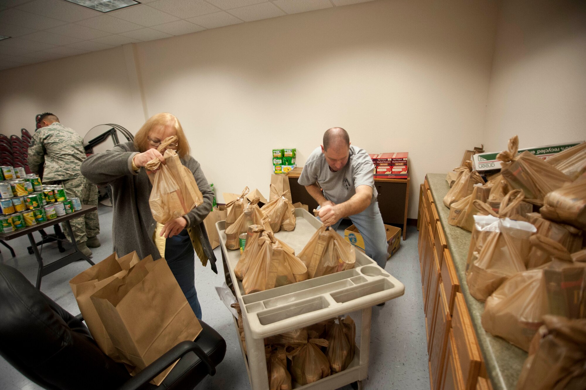 A food drive took place at the Airmen and Family Readiness Center here, so families could have the opportunity to enjoy a tasty holiday cheer Nov. 22-26. Around 7300 pounds of food and 249 turkeys were being prepared, as a gaggle of volunteers went around in a circle putting food supplies in bags. (U.S. Air force photo by Airman 1st Class Jelani Gibson) 
