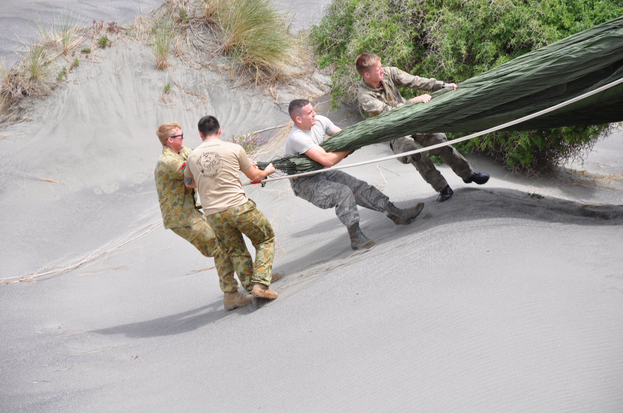 OHAKEA, New Zealand -- Multinational service members begin recovering the parachute from tactically-air-dropped cargo which landed just east of the drop zone during Exercise Kiwi Flag at the New Zealand Defence Force Raumi Drop Zone near Ohakea, New Zealand. Kiwi Flag personnel are supporting Exercise Southern Katipo -- held on New Zealand’s South Island. (U.S. Air Force photo by Senior Master Sgt. Denise Johnson/Released)