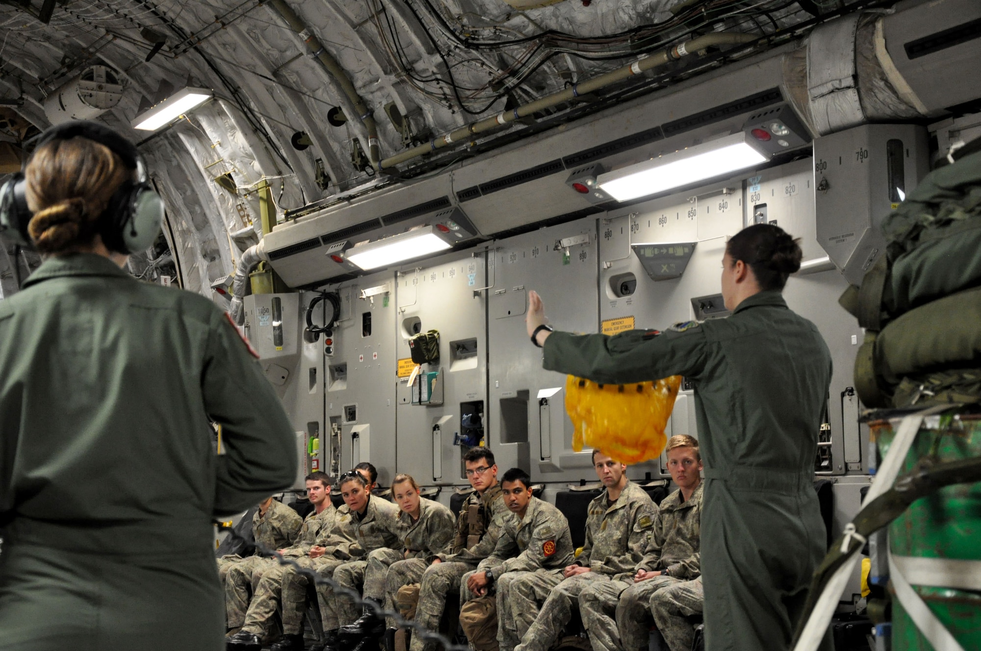 United States Air Force Senior Airman Alyse DeNittis (left) and Senior Airman Chelsea DiMarco provide a safety briefing to Royal New Zealand Air Force and New Zealand Army passengers during Exercise Kiwi Flag at RNZAF Base Ohakea, New Zealand, Nov. 21. The personnel are being transported to New Zealand’s South Island on a U.S. Air Force C-17 Globemaster III to support another exercise. Kiwi Flag is a multilateral RNZAF-sponsored tactical airlift exercise conducted in New Zealand. The Royal Australian Air Force, Republic of Singapore Air Force, and the French Armed Forces of New Caledonia also participated. DeNittis and DiMarco are both loadmasters deployed to the 517th Expeditionary Airlift Squadron from the 517th AS at Joint Base Elmendorf-Richardson, Alaska. DeNittis calls Charleston, S.C., home; DiMarco hails from San Antonio. Kiwi Flag personnel also provided cargo and passenger airlift including tactical air drops to Exercise Southern Katipo, New Zealand Defence Force’s largest-ever multilateral joint force amphibious exercise with eight other nations participating. (U.S. Air Force Photo by Senior Master Sgt. Denise Johnson/Released)