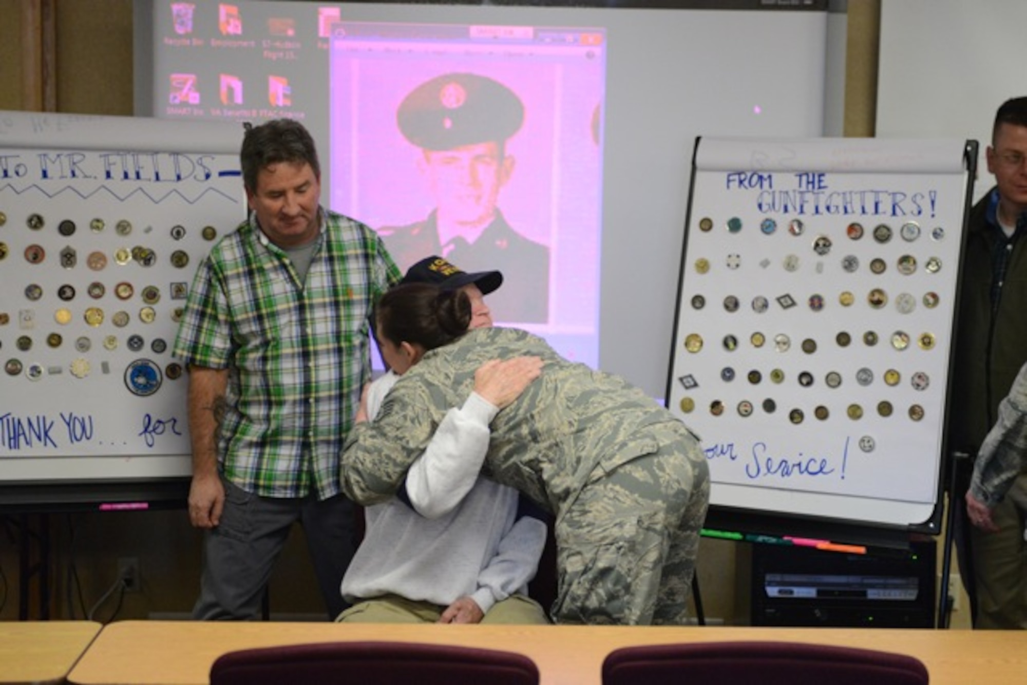 U. S. Air Force Staff Sgt. Ashelie Gross, 366th Security Forces Squadron NCO in charge of confinement, hugs Mr. Fields after a re-coining event Nov 27, 2013, at Mountain Home Air Force Base, Idaho. Fields was recently the victim of a burglery while he was hospitalized and every coin he received throughout his career was stolen. (U.S. Air Force photo by Senior Airman Benjamin Sutton/Released) 