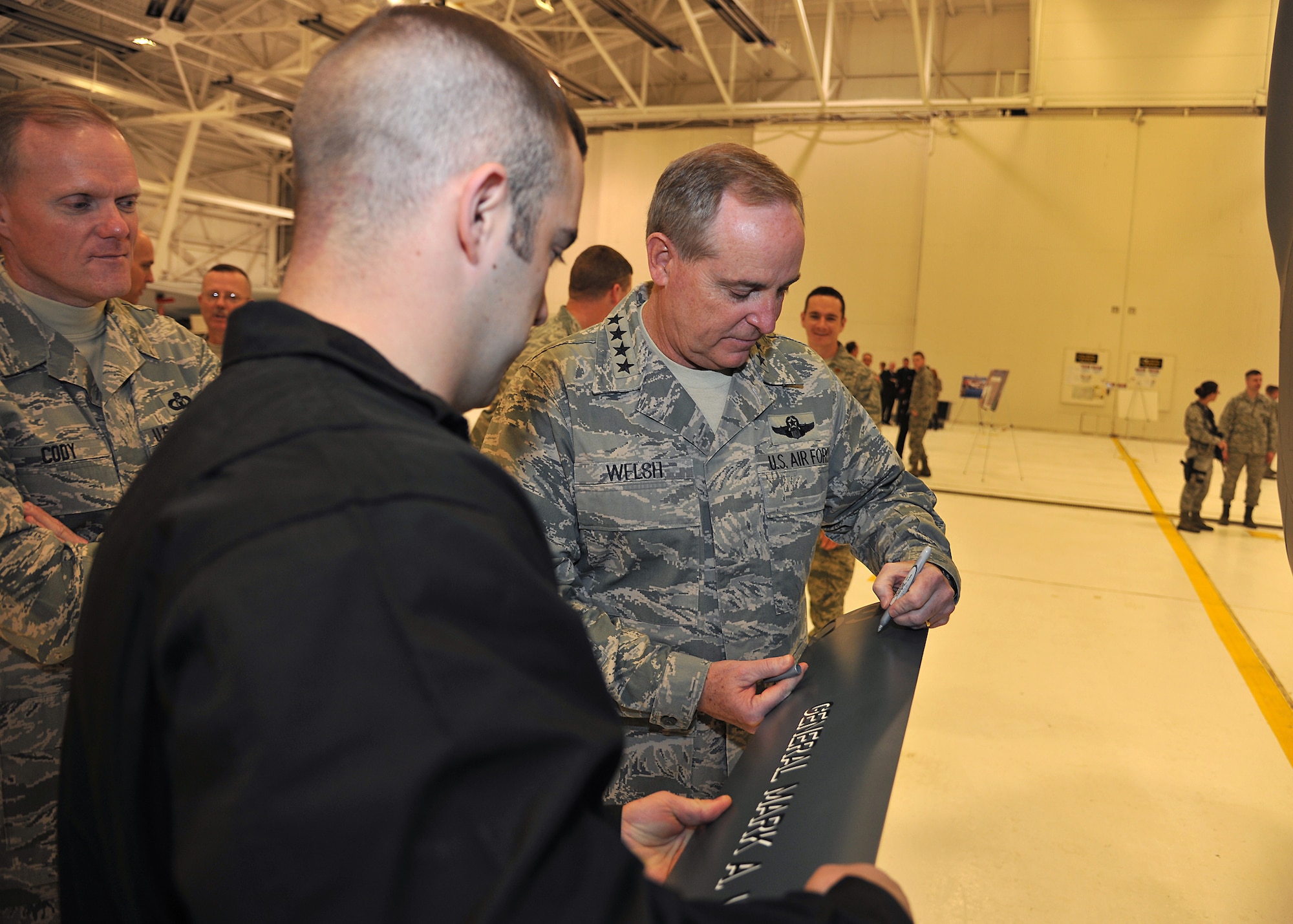 Air Force Chief of Staff Gen. Mark A. Welsh III signs the nose gear door of Block 40 Global Hawk aircraft, Nov. 26, 2013 on Grand Forks Air Force Base, N.D. A briefing on the Block 40 Global Hawk aircraft was part of the second day of the senior Air Force leadership’s official visit to the base. Welsh, his wife, Betty, along with Chief Master Sgt. of the Air Force James A. Cody, visited with Airmen and their families to thank them for their service and dedication. (U.S. Air Force photo/Senior Airman Xavier Navarro)