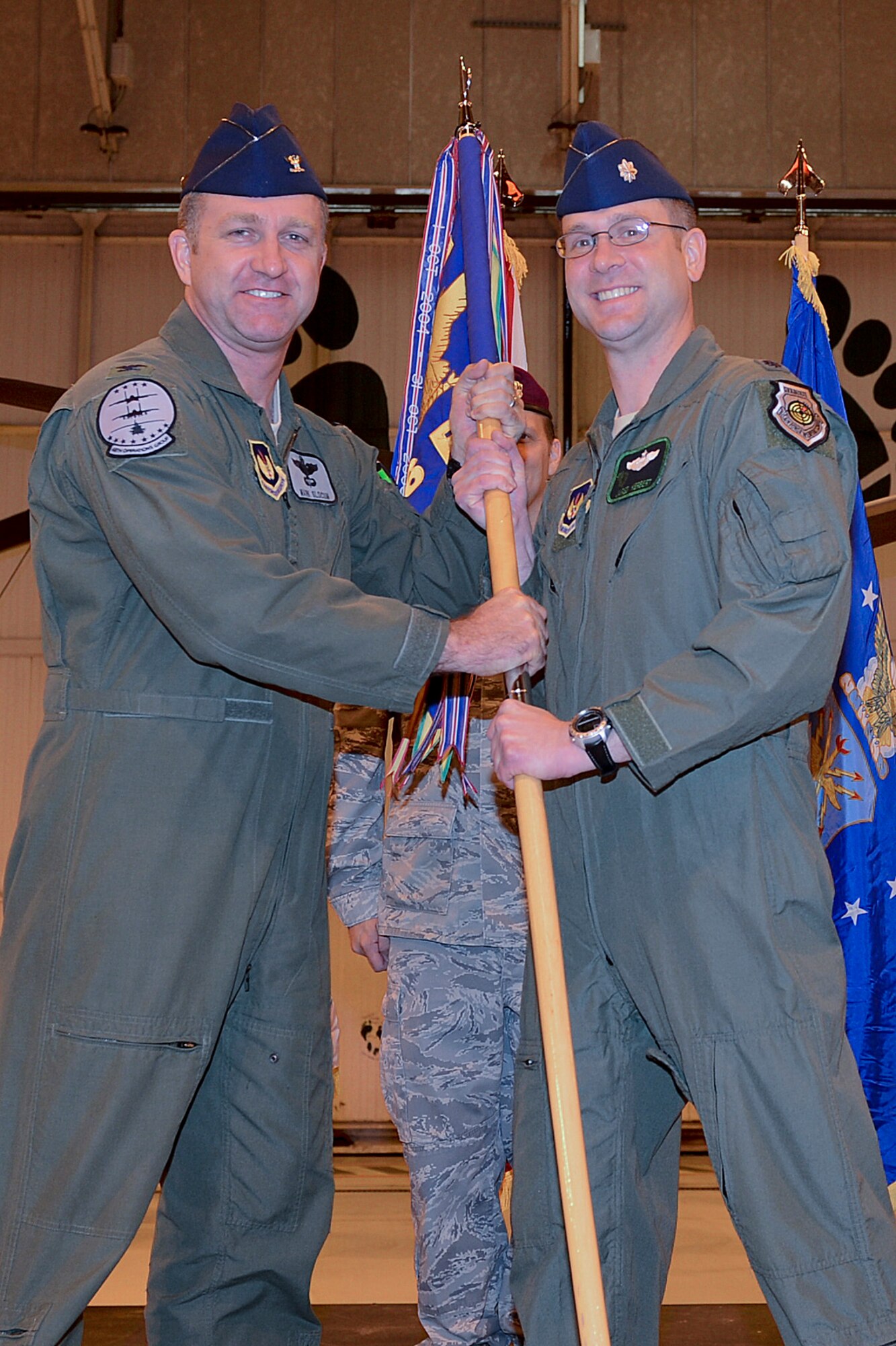 Col. Mark Slocum (left), 48th Operations Group commander, passes the guidon to Lt. Col. Jared Herbert as he takes command of the 56th Rescue Squadron at RAF Lakenheath, England, Nov. 26, 2013. The change of command ceremony is a tradition that represents a formal transfer of authority and responsibility. (U.S. Air Force photo by Airman 1st Class Trevor T. McBride/Released)