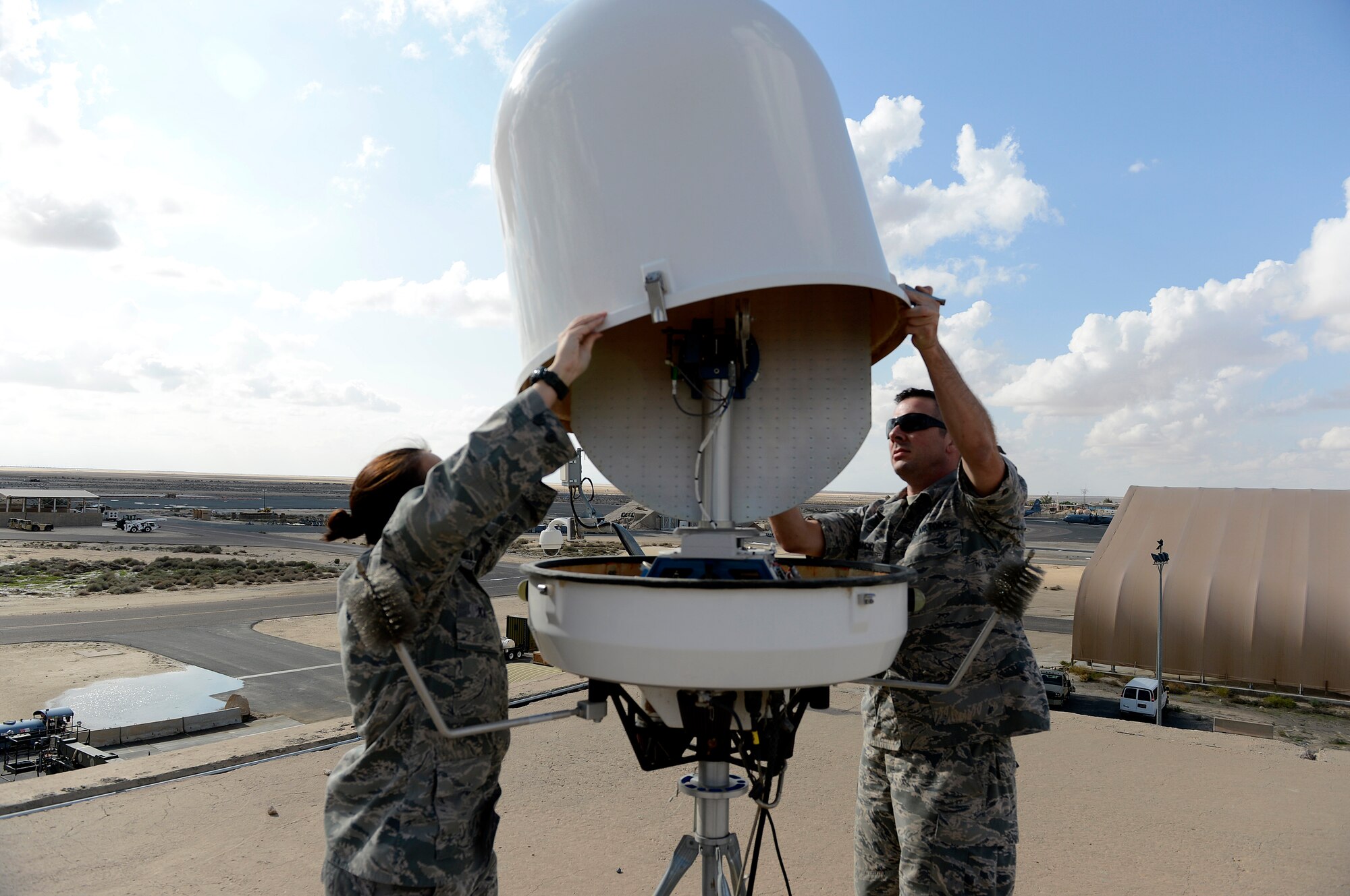 Staff Sgts. Tina Kay and David Glowacki (from left to right), 386th Expeditionary Operations Support Squadron, weather flight technicians; remove the radome cover off the E700XD Portable Doppler Radar (PDR) to perform preventative monthly maintenance here, Nov. 21, 2013.  This PDR provides the sole radar coverage for coalition forces in the local area. Glowacki is deployed out of the 437th Operations Support Squadron, Joint Base Charleston, Charleston, S.C., and is a native of Buffalo, N. Y. Kay is deployed out of the 319th Operations Support Squadron, Grand Forks Air Force Base, Grand Forks, N.D., and is a native of Mobile, Ala. (U.S. Air Force photo by Master Sgt. Christopher A. Campbell)
