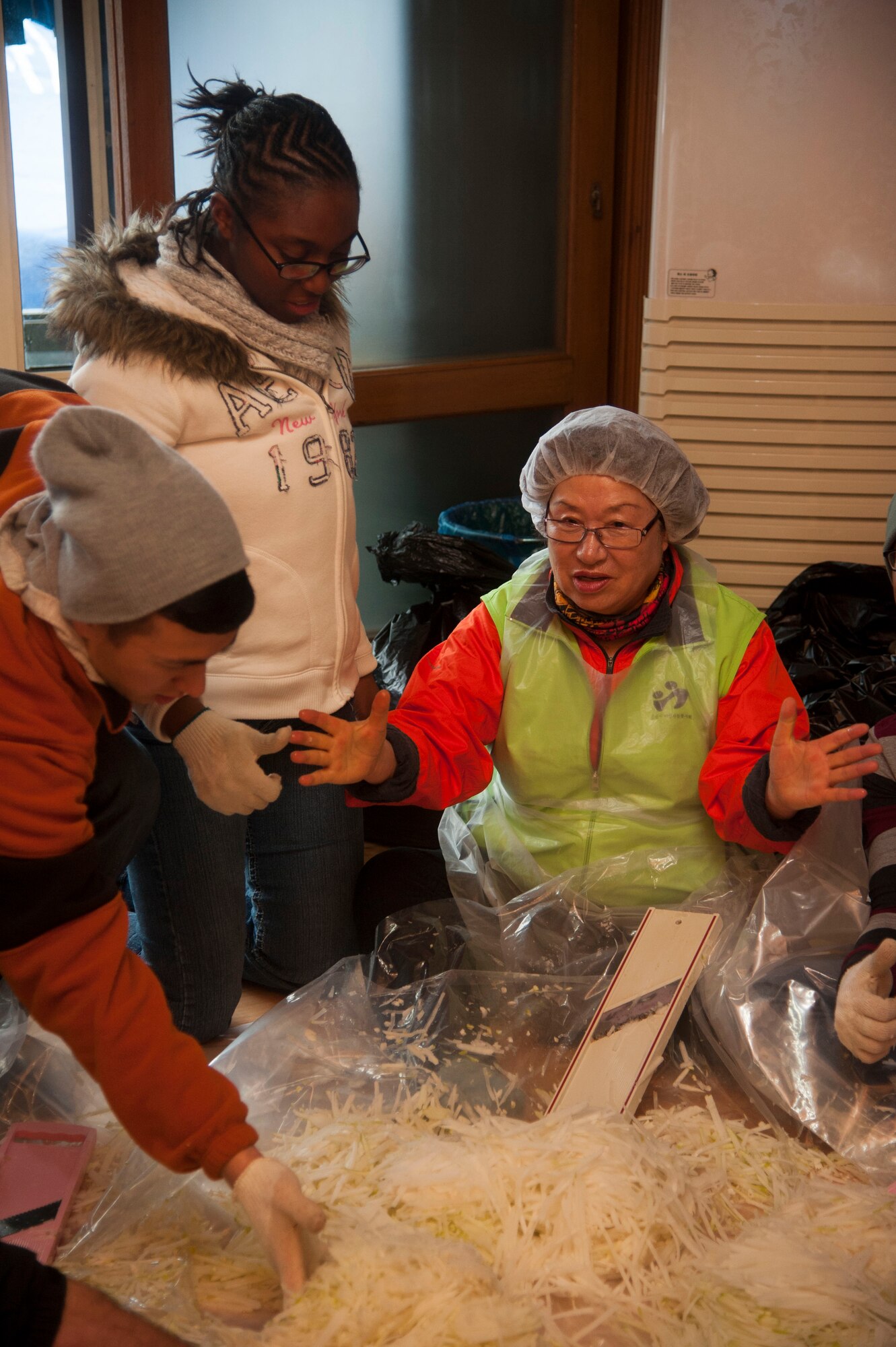 Airmen assigned to both the 8th Medical Group and the 8th Maintenance Group assist with cutting daikon radishes, Nov. 27, 2013, at a Women’s Volunteer Center that provides kimchee for the homeless and needy in Gunsan, Republic of Korea. The Wolf Pack focused on the well-being of others as part of becoming resilient. (U.S. Air Force photo by Staff Sgt. Jessica Haas/Released) 
