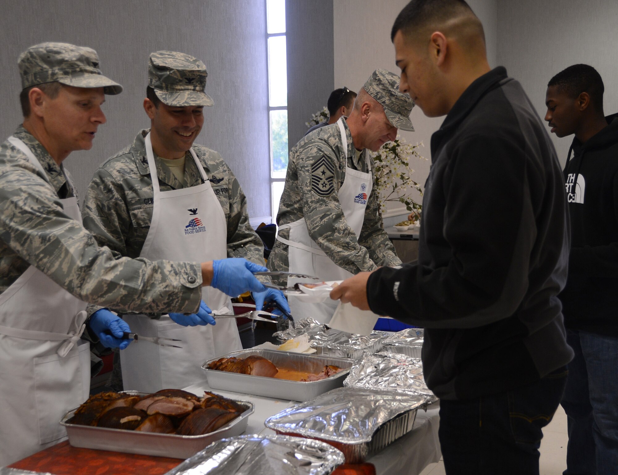 Airmen are served turkey and ham by base leadership during a Thanksgiving luncheon for dorm Airmen on Barksdale Air Force Base, La., Nov. 28, 2013. The First Sergeant’s Council held the luncheon for the Airman and base leadership and volunteers prepared and served the food. (U.S. Air Force photo/Staff Sgt. Amber Corcoran)