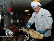 U.S. Air Force Airman 1st Class Daniel Csiti, 100th Force Support Squadron food specialist, transfers bread rolls to serving dishes for the Thanksgiving lunch Nov. 28, 2013, held at the Gateway Dining Facility on RAF Mildenhall, England. The cooks prepared lunch for approximately 250 members of Team Mildenhall. (U.S. Air Force photo by Senior Airman Kate Maurer/Released)