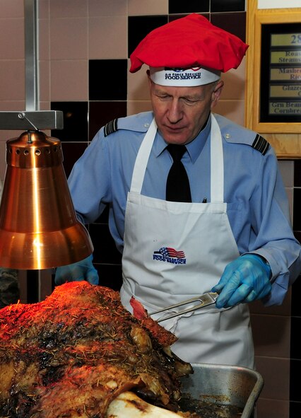 Royal Air Force Sqn. Ldr. Rick Fryer, RAF Mildenhall station commander, carves roast beef during the Thanksgiving lunch served in celebration of the American holiday Nov. 28, 2013, at the Gateway Dining Facility on RAF Mildenhall, England. The dining facility hosted the event, where several distinguished visitors joined the dining facility staff to serve lunch to approximately 250 members of Team Mildenhall. (U.S. Air Force photo by Senior Airman Kate Maurer/Released)