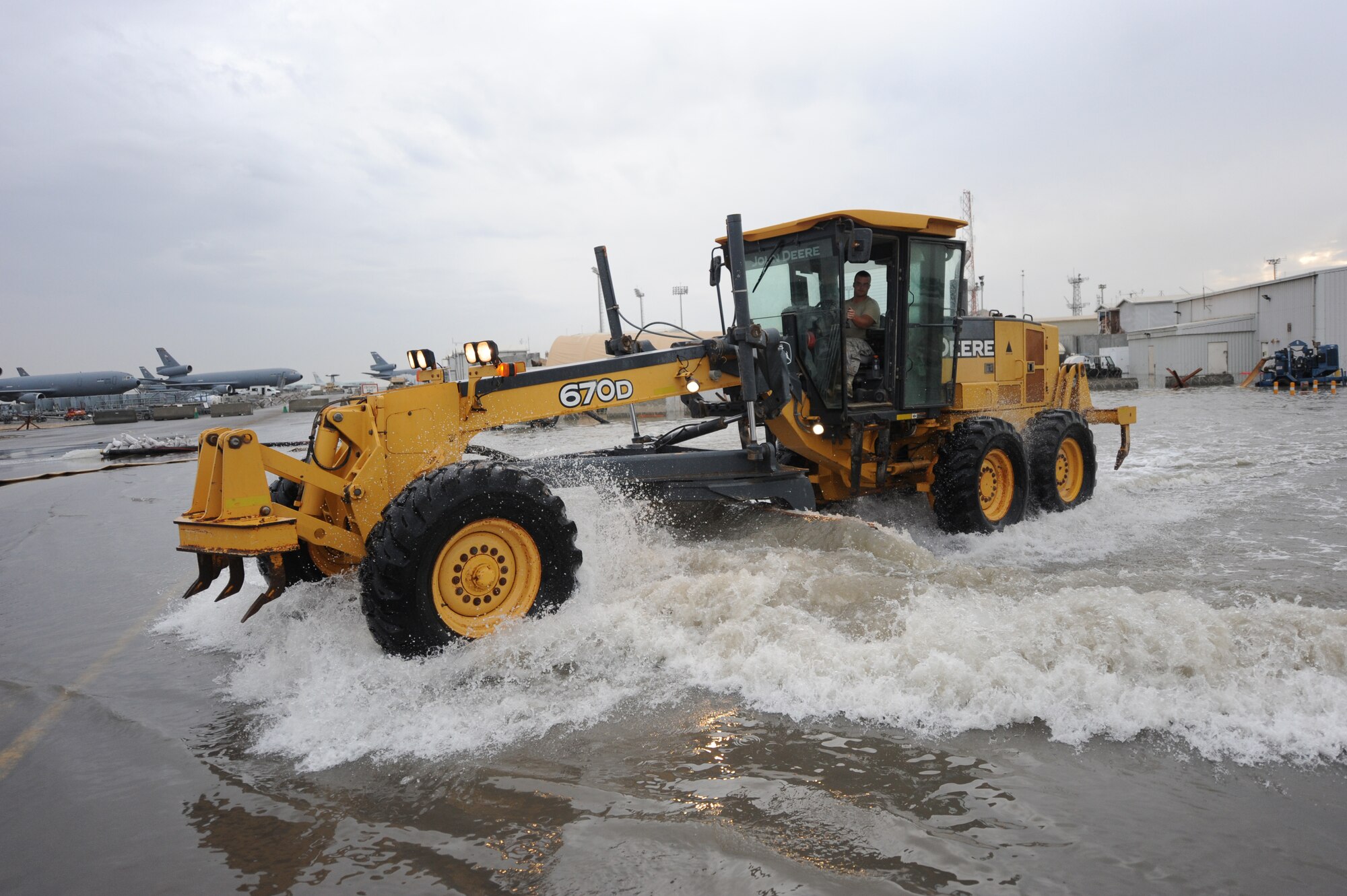 A heavy equipment operator with the 380th Expeditionary Civil Engineer Squadron uses a grader to remove water from a low spot on base after a minor flood at an undisclosed location in Southwest Asia Nov. 21, 2013. A high water table and drainage from the flightline left a few buildings with a little over a foot of water after rainfall here. (U.S. Air Force photo by Staff Sgt. Jacob Morgan)