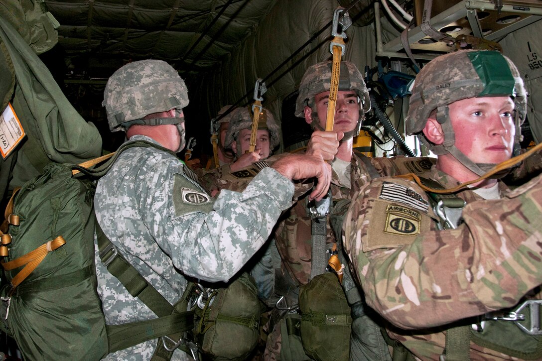 Paratroopers hold on to their static lines as they prepare to exit a C-130 aircraft during airborne training on Fort Bragg, N.C., Nov. 21, 2013.