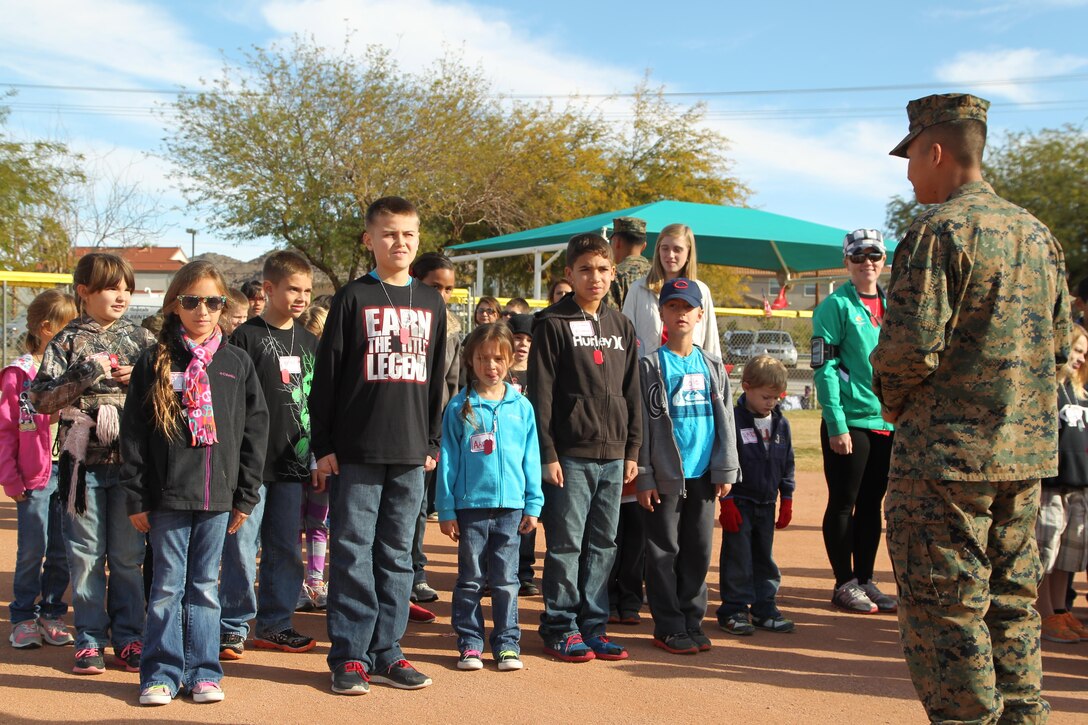 Lance Cpl. Huy Nguyen, aircraft maintenance administration specialist, Unmanned Aerial Vehicle Squadron 3, instructs Combat Center children on how to make a proper formation during a mock combined-arms exercise for kids at Felix Field Nov. 26, 2013.