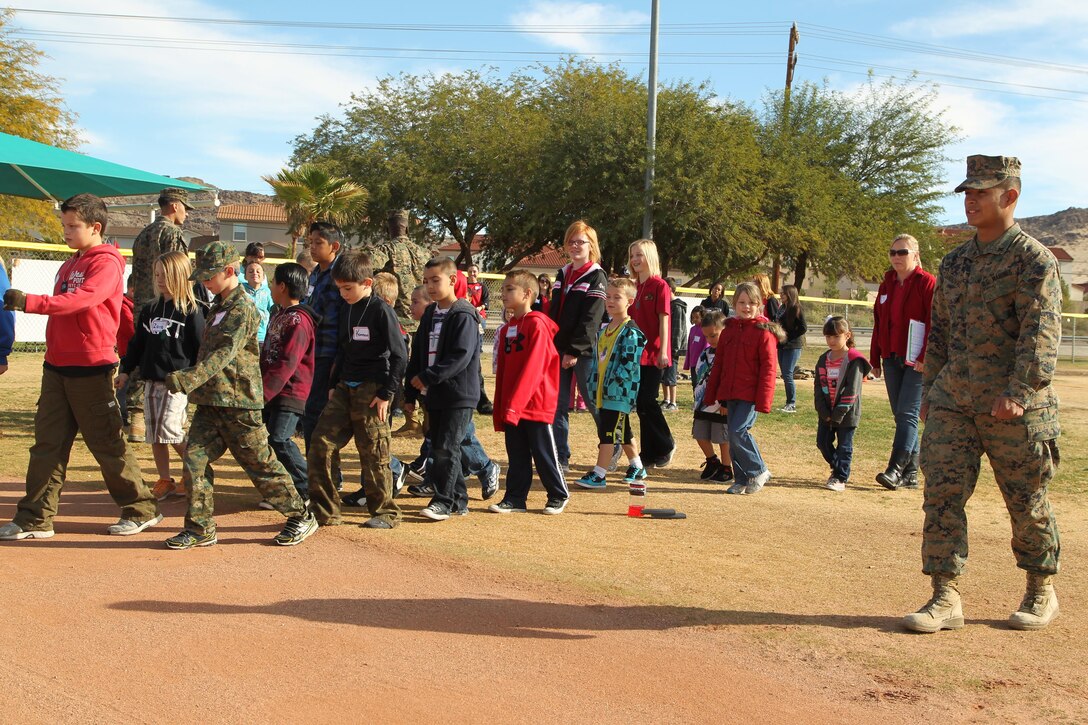 Lance Cpl. Ignacio Sandoval, electrician, Unmanned Aerial Vehicle Squadron 3, leads a group of Combat Center children on a march during a mock combined-arms exercise for kids at Felix Field Nov. 26, 2013.