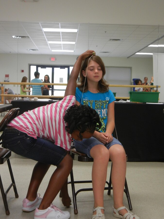 Elisa uses string to measure the seated height of fellow fifth-grader Alexandra during the Crime Scene Investigator Workshop put on by the Tiger Woods Learning Center on Sept. 21, 2013. Students attending the workshop at the Quantico Youth Center learned how, before the use of fingerprints, investigators used body measurements to identify suspects. 