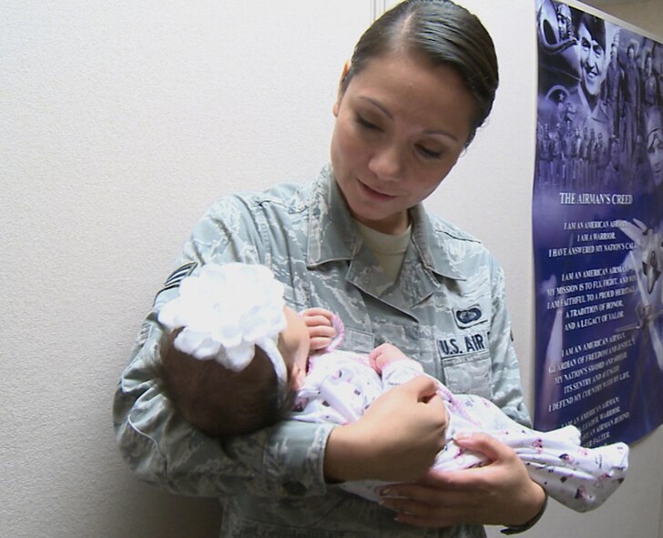 Senior Airman Karina Reyes, 2nd Contracting Squadron services contract specialist, holds the newborn daughter of Master Sgt. Gary Frank and his wife Ylenia at the 2nd CONS fiscal year soft closeout on Barksdale Air Force Base, Sept. 20, 2013. Sergeant Frank is deployed and has yet to meet his new daughter, but the unit has been working to make sure Mrs. Frank knows she has wingmen she can count on during his absence. (U.S. Air Force video image/Airman 1st Class Samuel O?Brien)