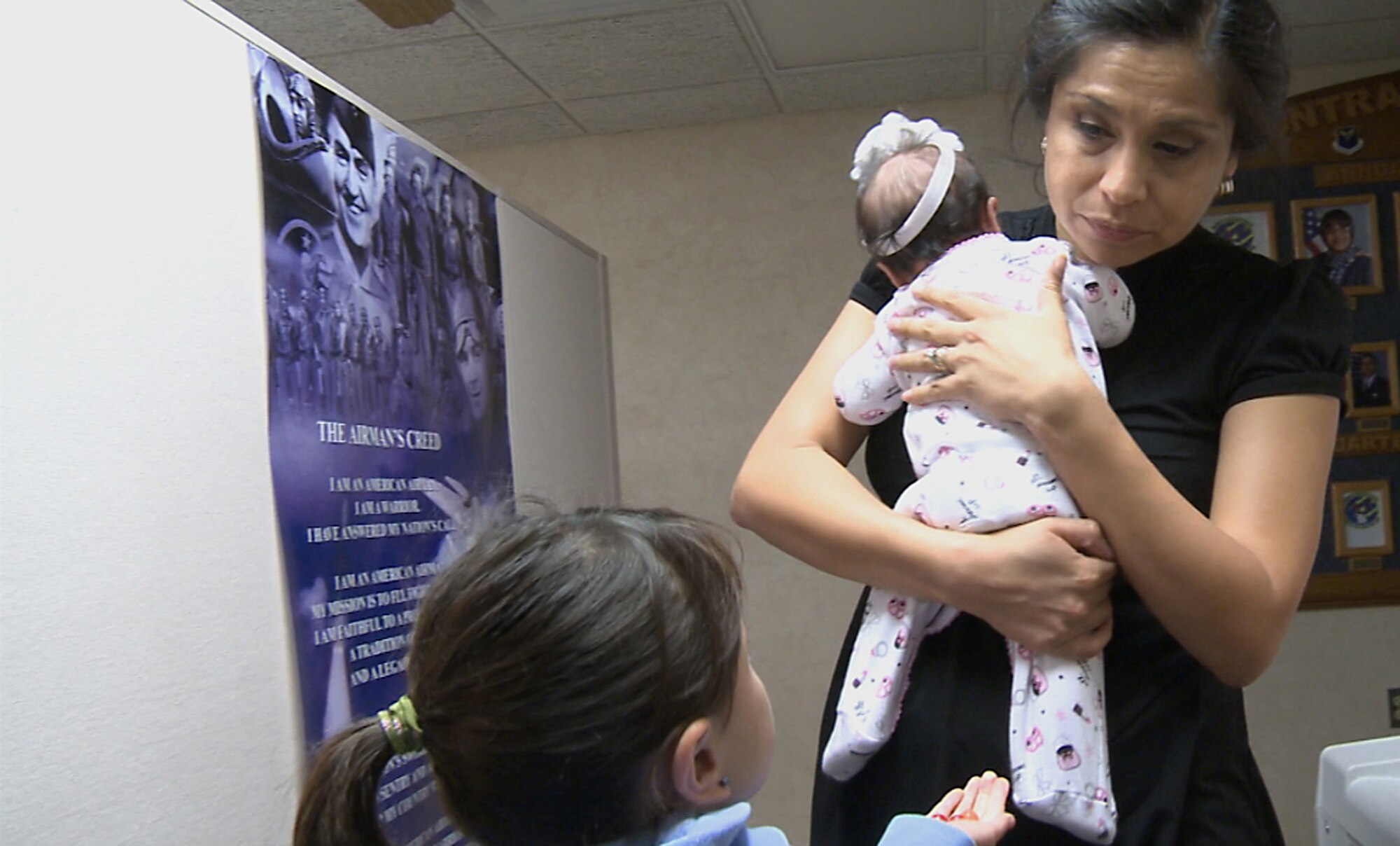 Ylenia Frank, wife of Master Sgt. Gary Frank, 2nd Contracting Squadron commodities flight chief, holds her newborn daughter while speaking with one of her other children at the 2nd CONS fiscal year soft closeout on Barksdale Air Force Base, Sept. 20, 2013. Sergeant Frank is currently deployed, and the 2nd CONS invited Mrs. Frank to the unit during a long shift to share a meal and help put together a care package for her husband. (U.S. Air Force video image/Airman 1st Class Samuel O?Brien)